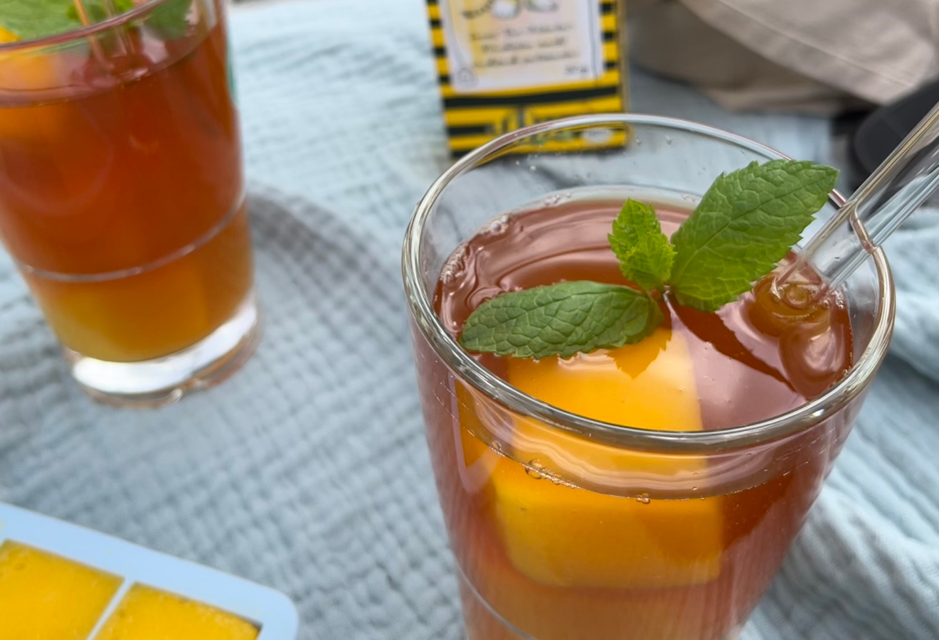 Eistee für kleine Tiger mit Mangostückchen und Minzblättern in einem Glas