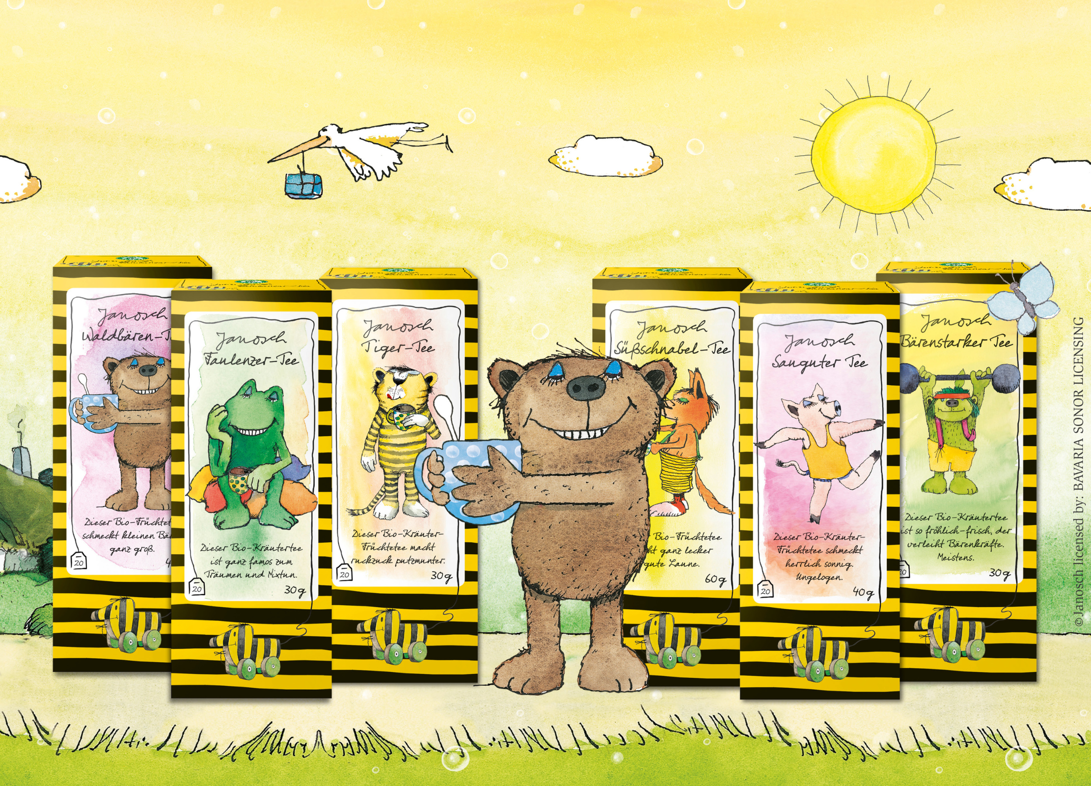 Fünf farbenfrohe Teepackungen mit Janosch-Figuren stehen vor gelbem Hintergrund in der Sonne, in der Mitte ein lächelnder Bär mit Teetasse