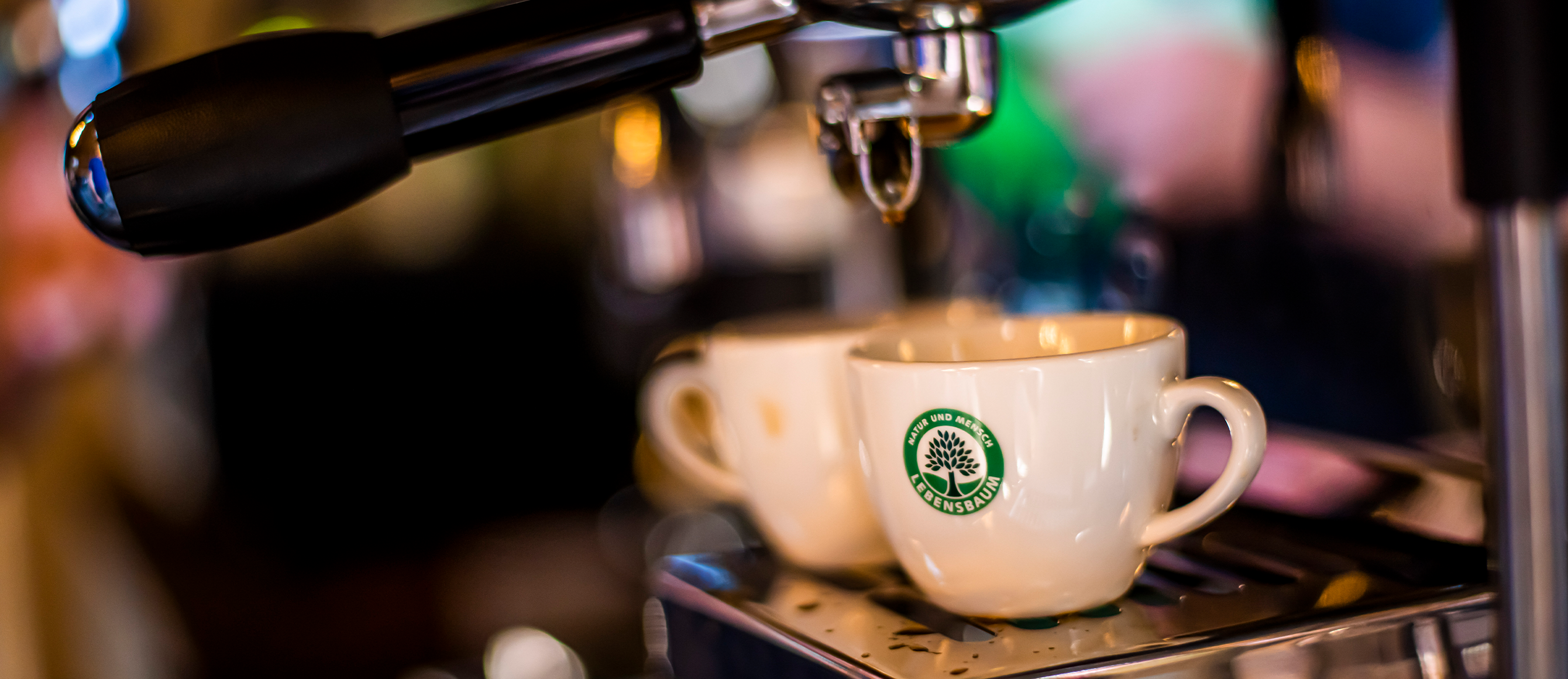 Zwei Lebensbaum-Espressotassen unter einer Siebträger-Maschine