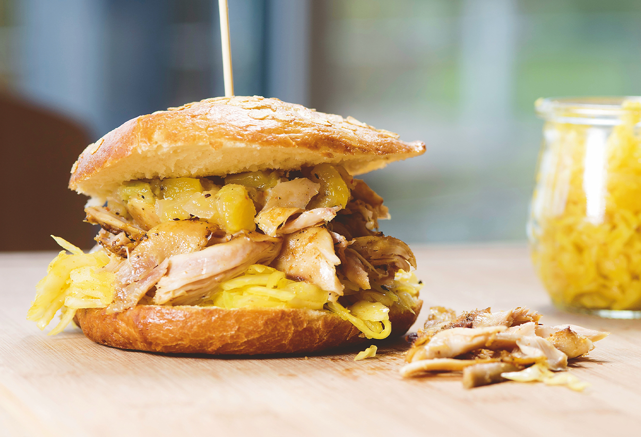 Pulled-Chicken-Burger auf einem Holzbrett