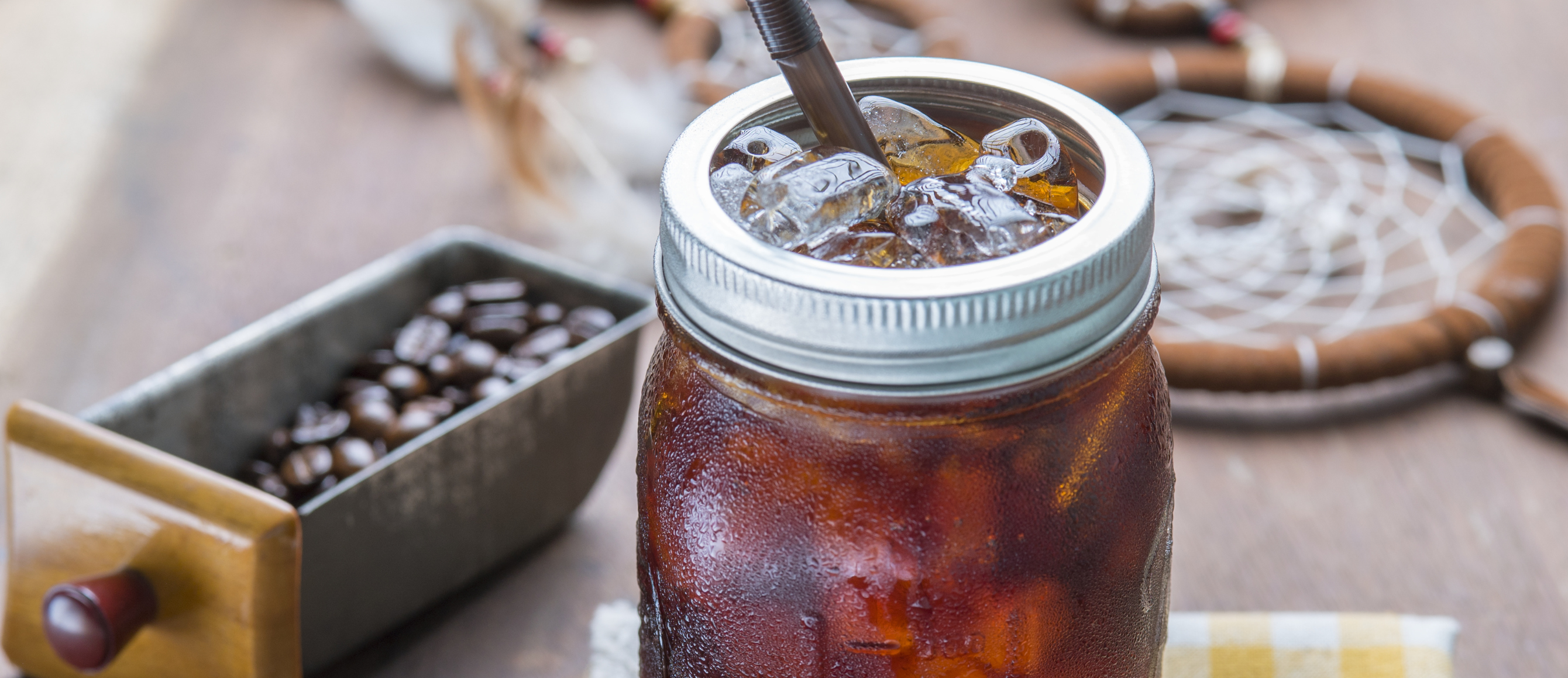 Cold Brew Kaffee mit Eiswürfeln in einem Glas mit Schraubdeckel und Strohhalm