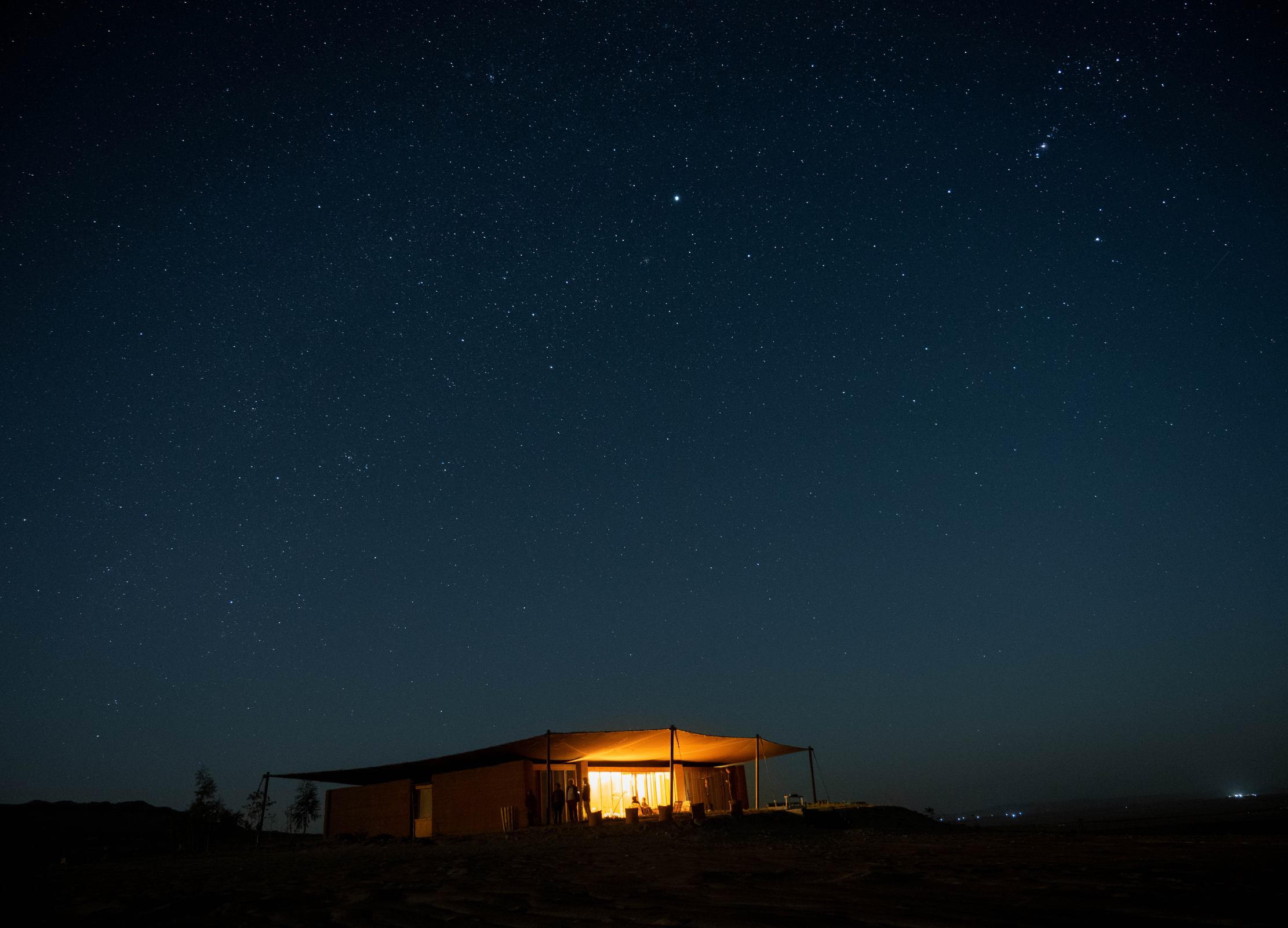 Ein beleuchtetes Wüstenhaus bei Nacht unter einem klaren Sternenhimmel in Ägypten
