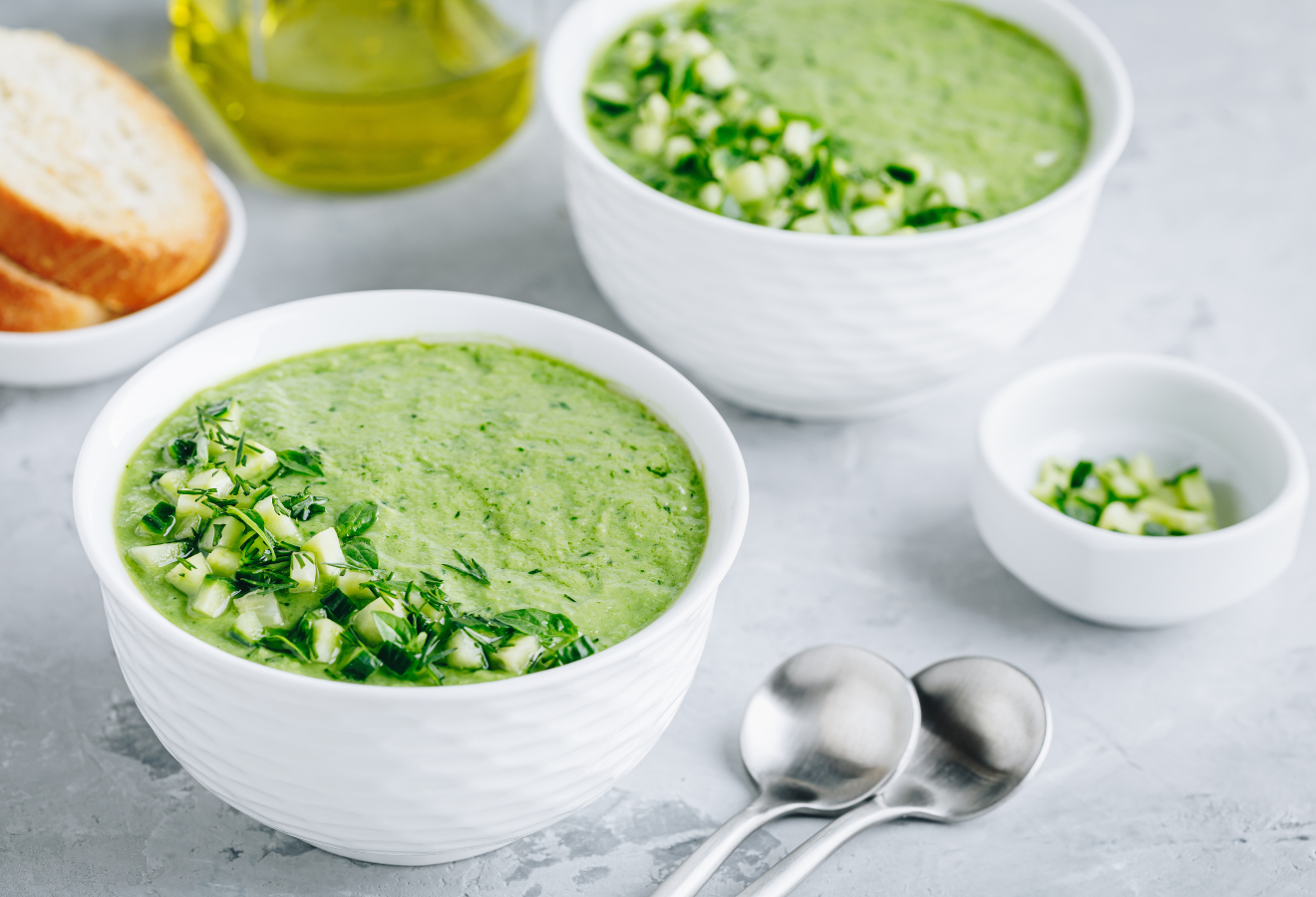 Gurken-Sellerie-Gazpacho in zwei weißen Schüsseln mit Gurkenwürfeln garniert