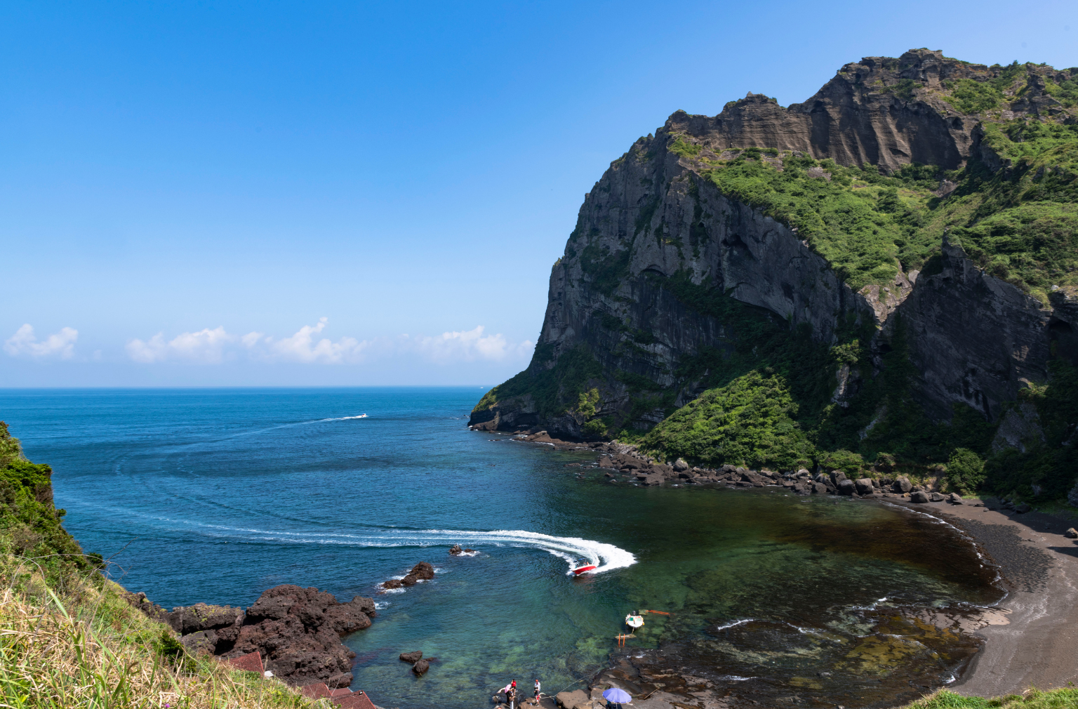 Küste mit grünem Felsen, Bucht und Boot auf dem blauen Meer in Südkorea