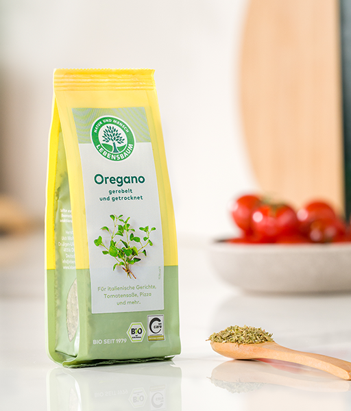 Kategoriebild für Kräuter und Kräutermischungen von LEBENSBAUM, Oregano-Verpackung auf einer Küchenzeile neben einem Löffel mit getrockentem Oregano