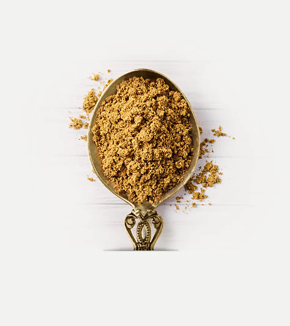 Garam Masala Gewürzmischung in goldenem Pulver auf antiker Messlöffel mit verstreutem Gewürz auf weißem Hintergrund.