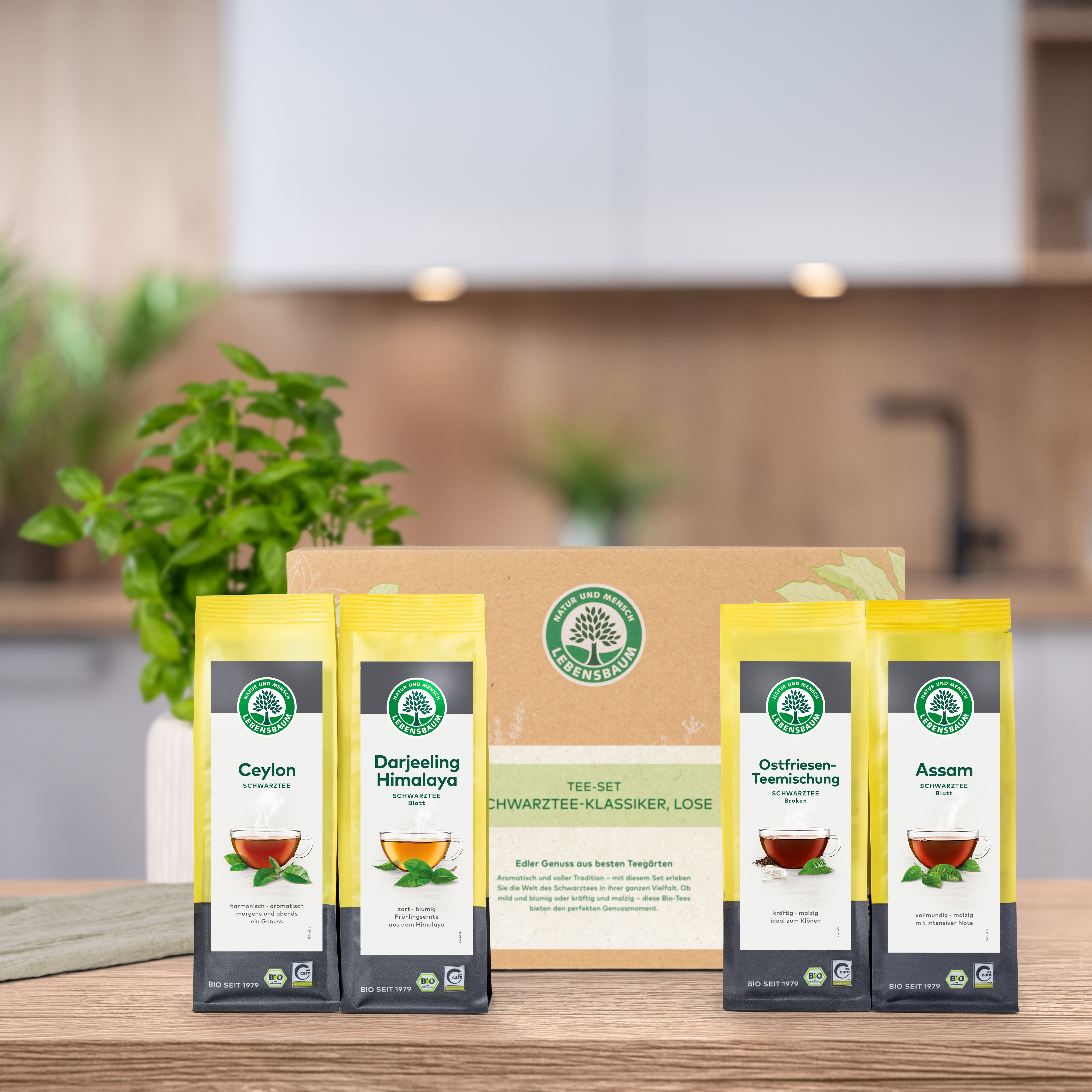 Verschlossenes Geschenk-Set steht auf einem Holztisch in der Küche. Vor der Geschenk-Set Verpackung  stehen die darin enthaltenen Produkte