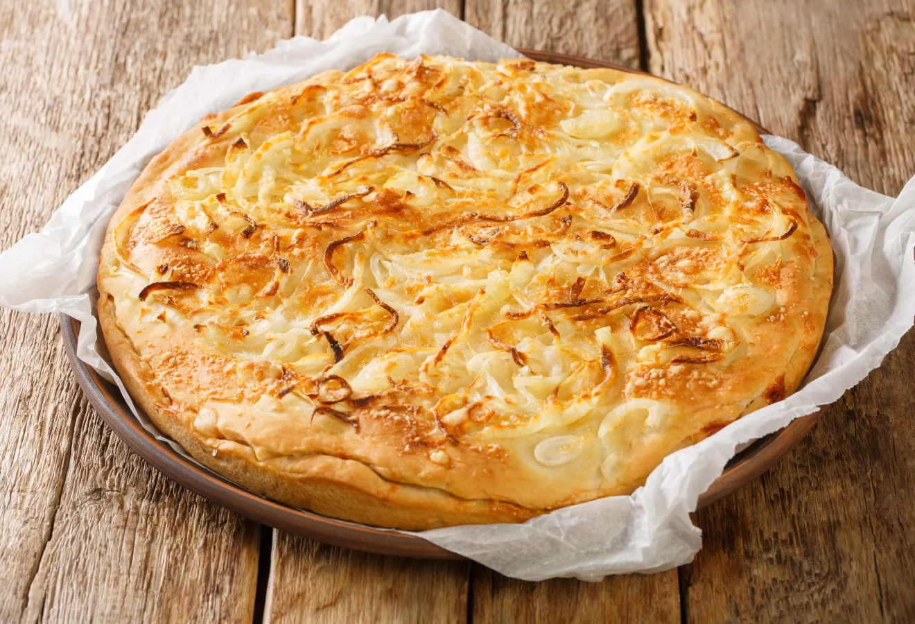 Zwiebel-Käse-Focaccia auf einem Holzteller mit Backpapier