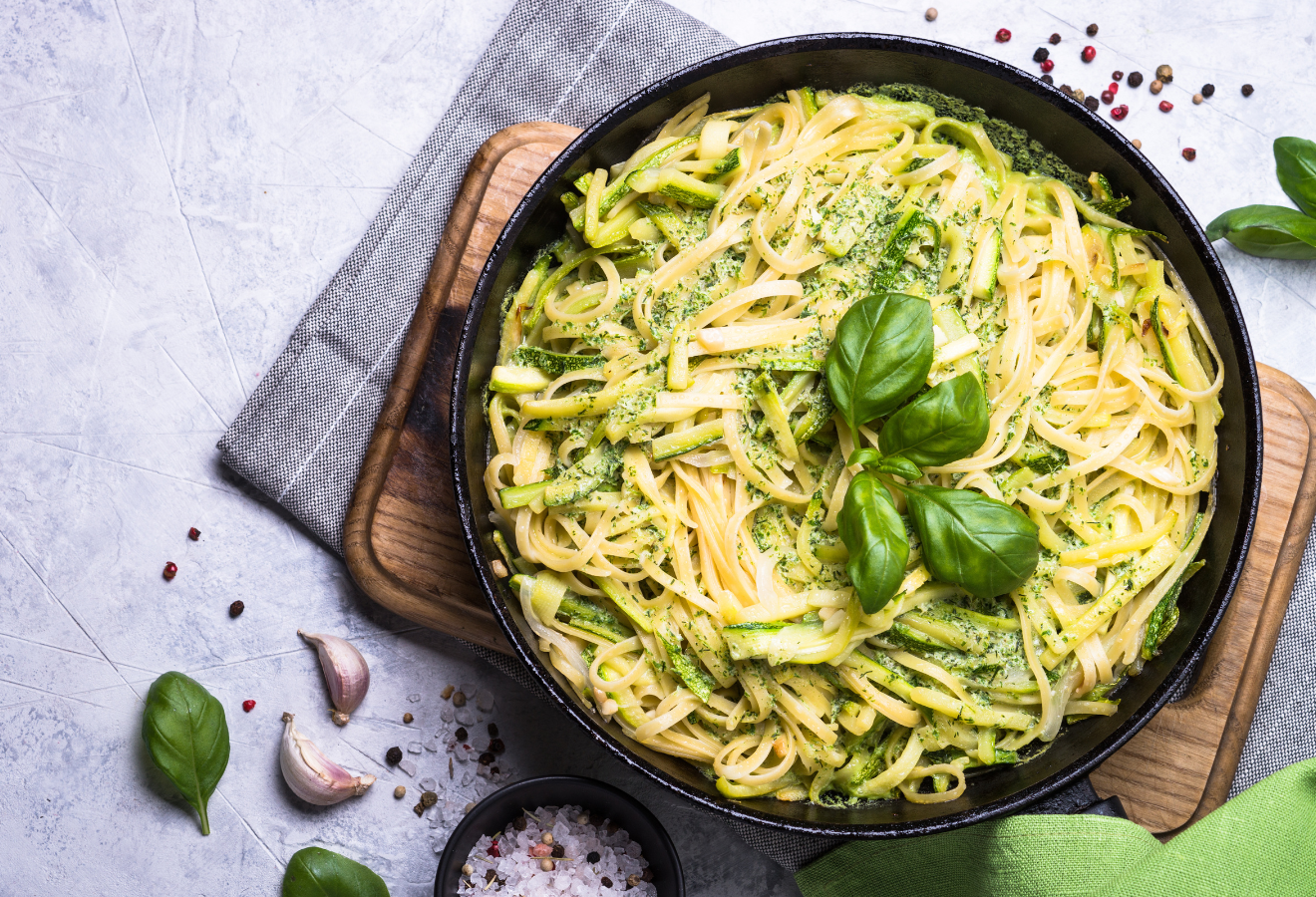 Zucchini-Pasta Aglio e Olio in einer schwarzen Pfanne mit Basilikum garniert