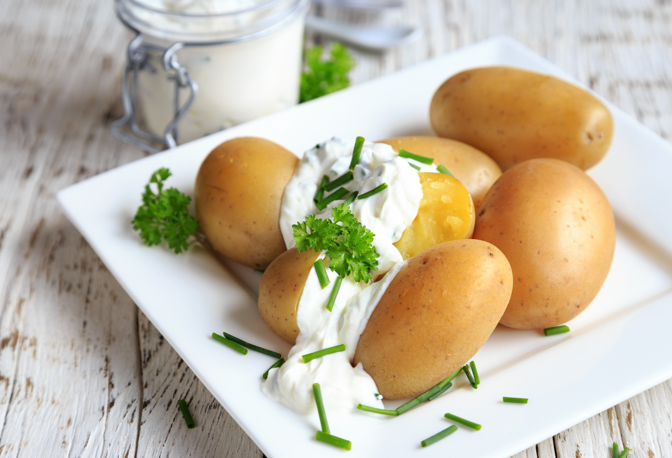 Pellkartoffeln mit Quark auf einem weißen Teller mit Schnittlauch und Petersilie garniert