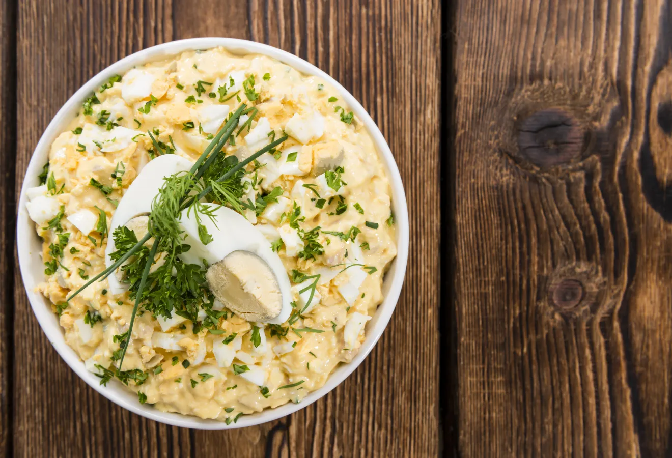 Frühstückseiersalat mit gekochten Eiern und Kräutern garniert in einer weißen Schale