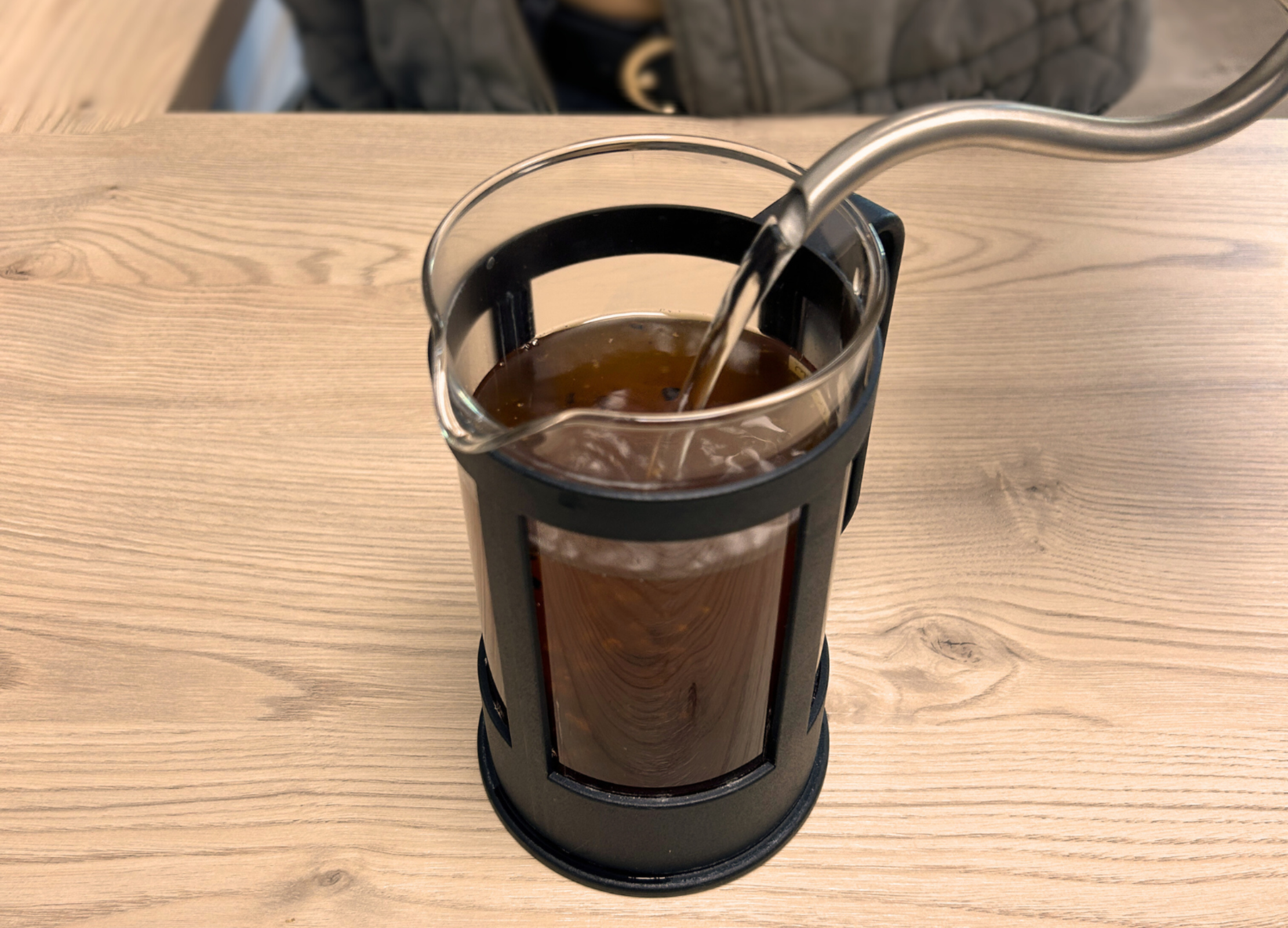 Heißes Wasser wird in eine French Press mit gemahlenem Kaffee gegossen