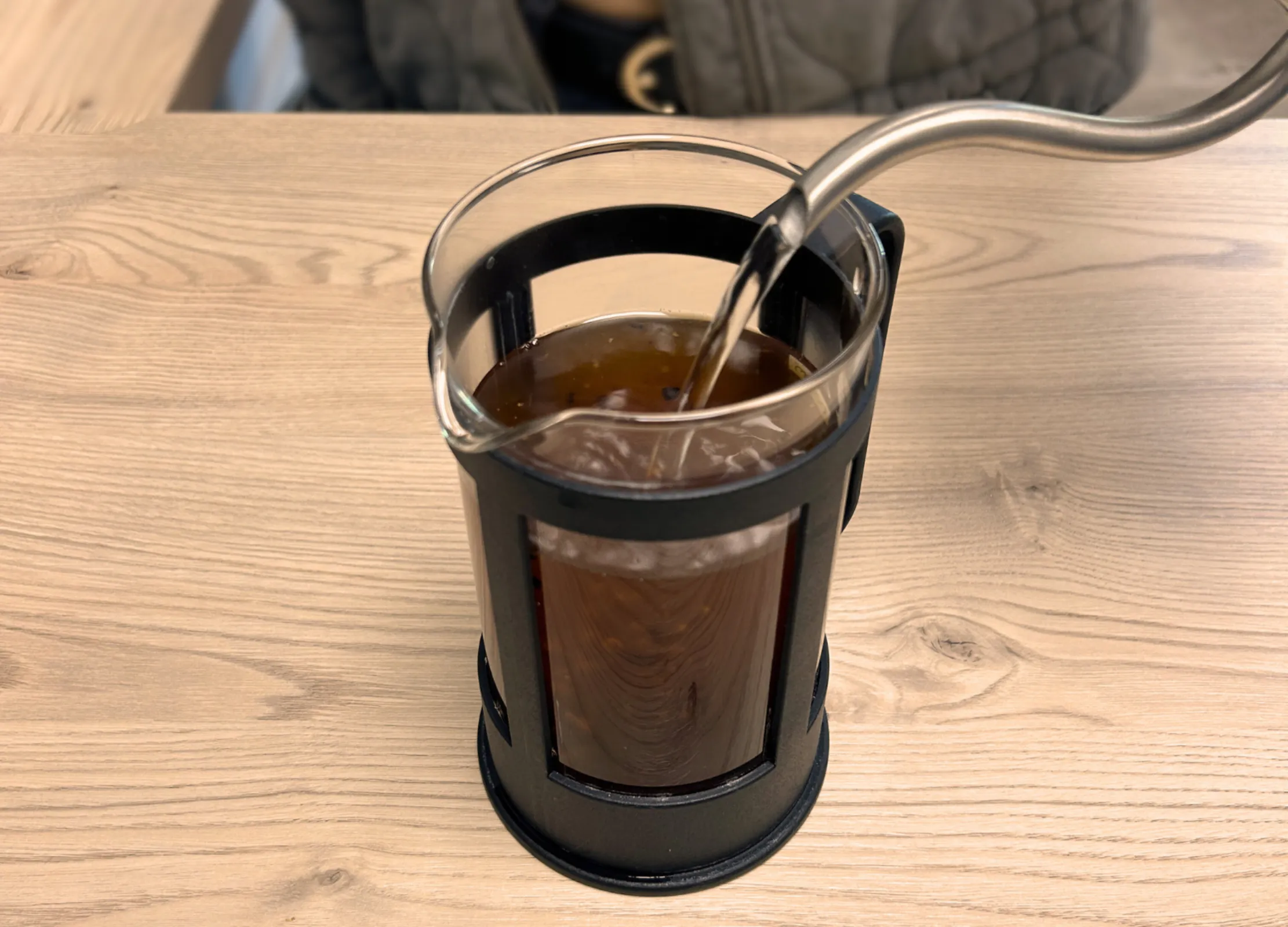 Heißes Wasser wird in eine French Press mit gemahlenem Kaffee gegossen