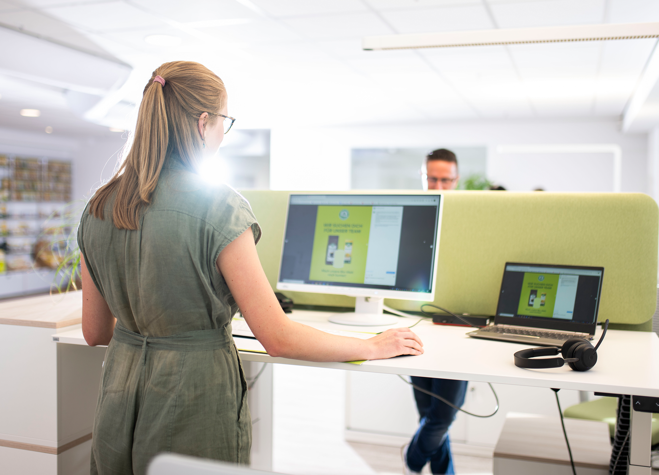 Frau steht an einem höhenverstellbaren Schreibtisch in unserem modernen Büro in Diepholz und arbeitet am Computer