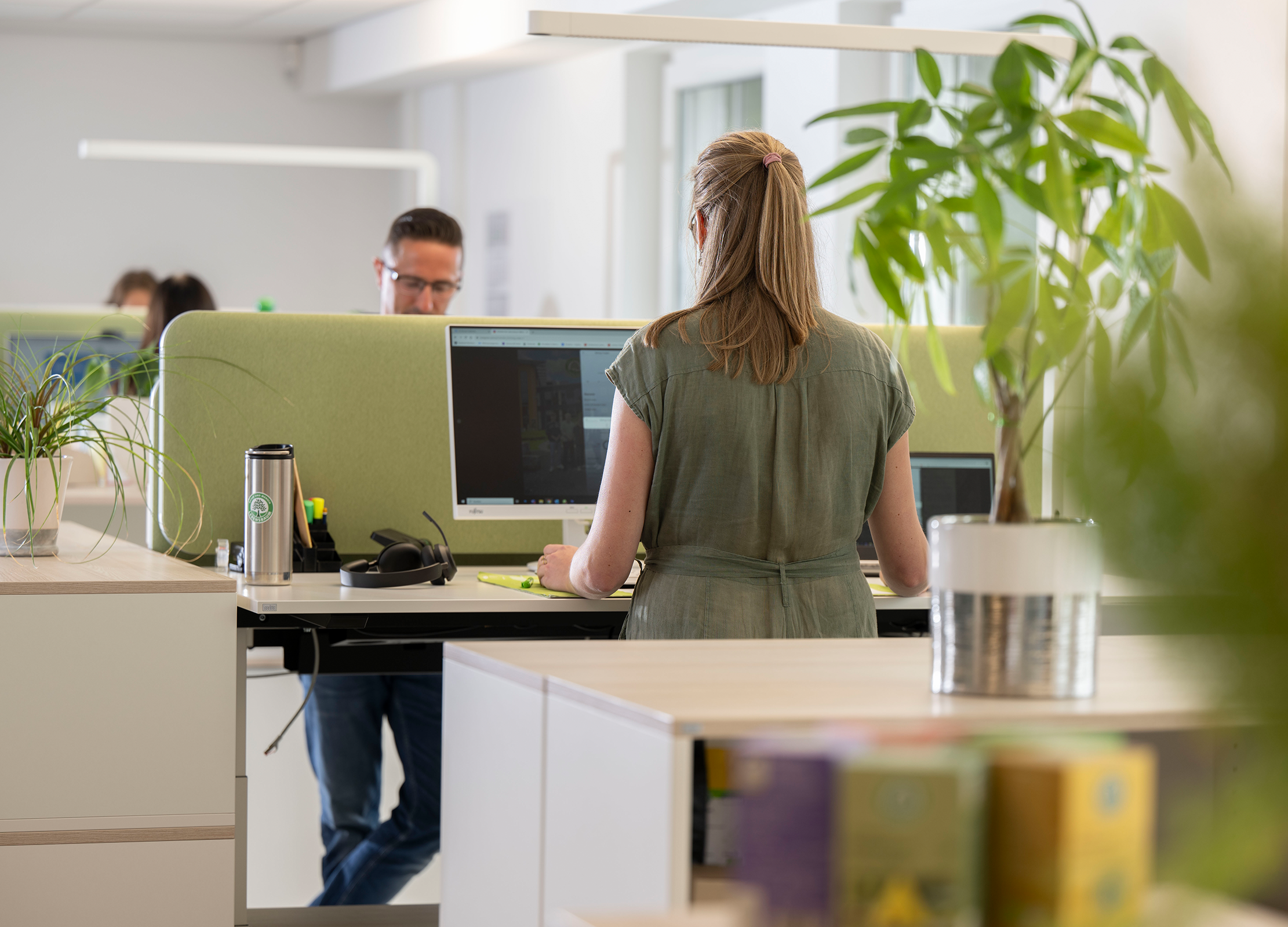 Frau steht an einem höhenverstellbaren Schreibtisch in unserem modernen Büro in Diepholz und arbeitet am Computer