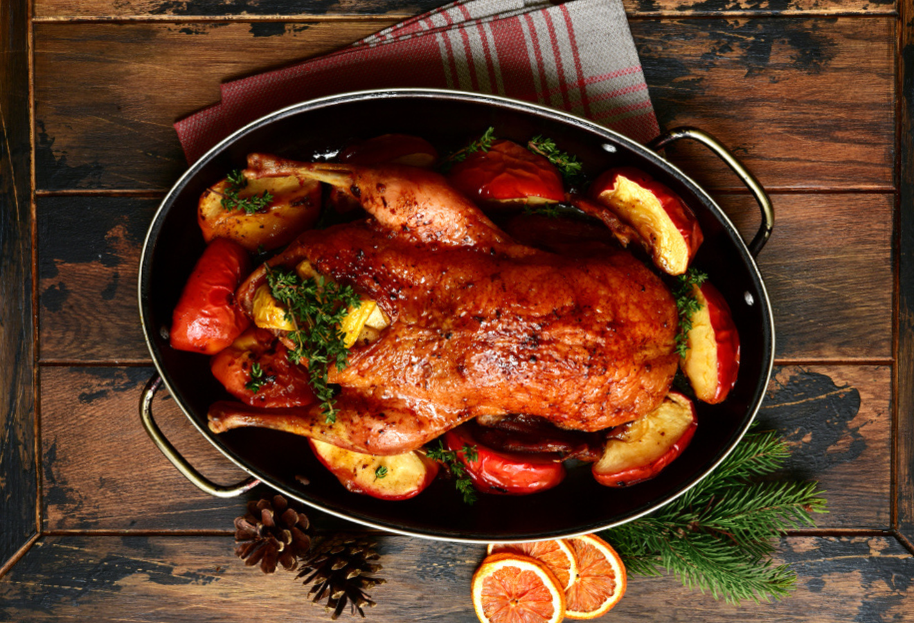 Ente mit Apfel-Orangen-Füllung in einer schwarzen Ofenform mit Apfelspalten