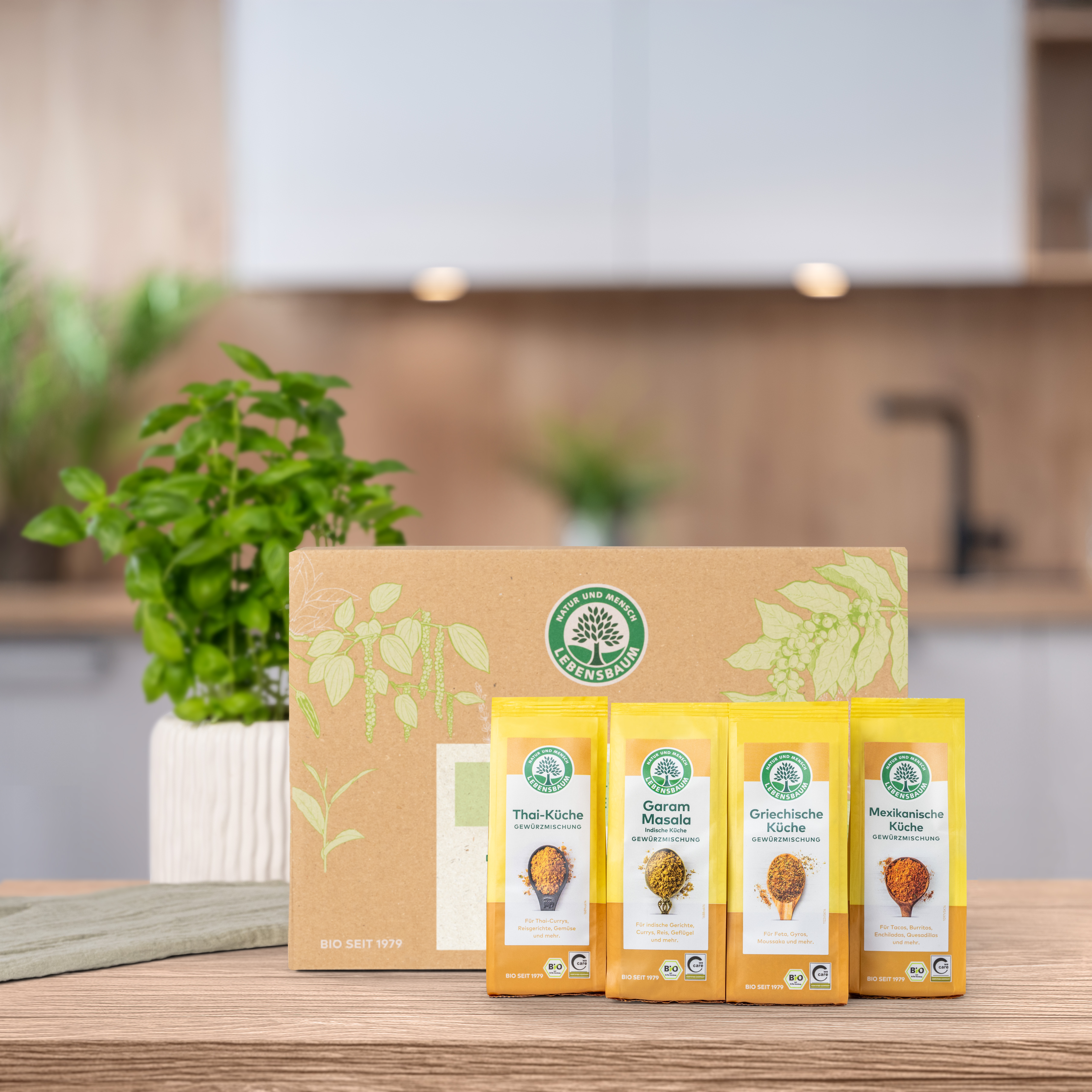 Verschlossenes Geschenk-Set steht auf einem Holztisch in der Küche. Vor der Geschenk-Set Verpackung  stehen die darin enthaltenen Produkte