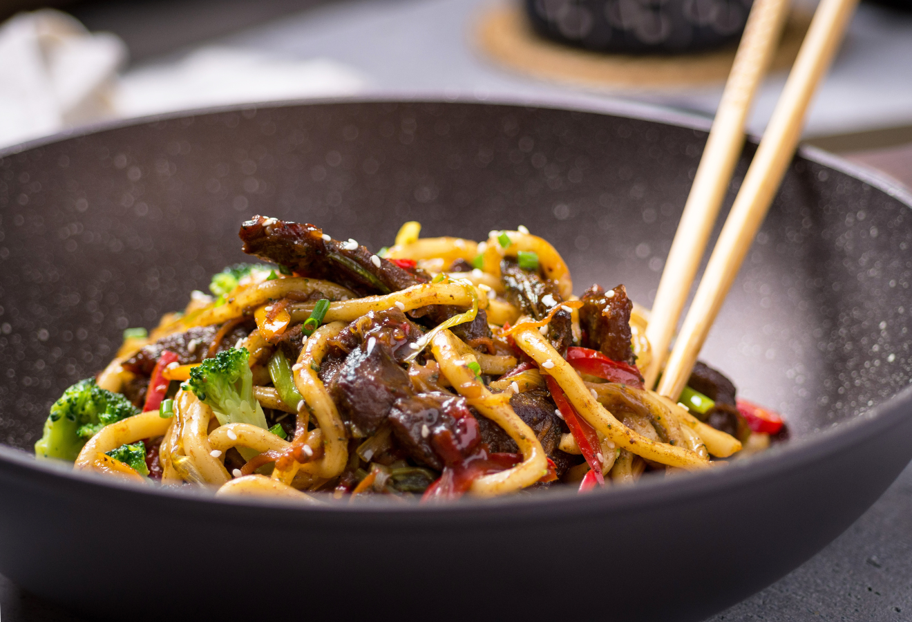 Stir-Fry in einer schwarzen Schüssel mit Essstäbchen darin