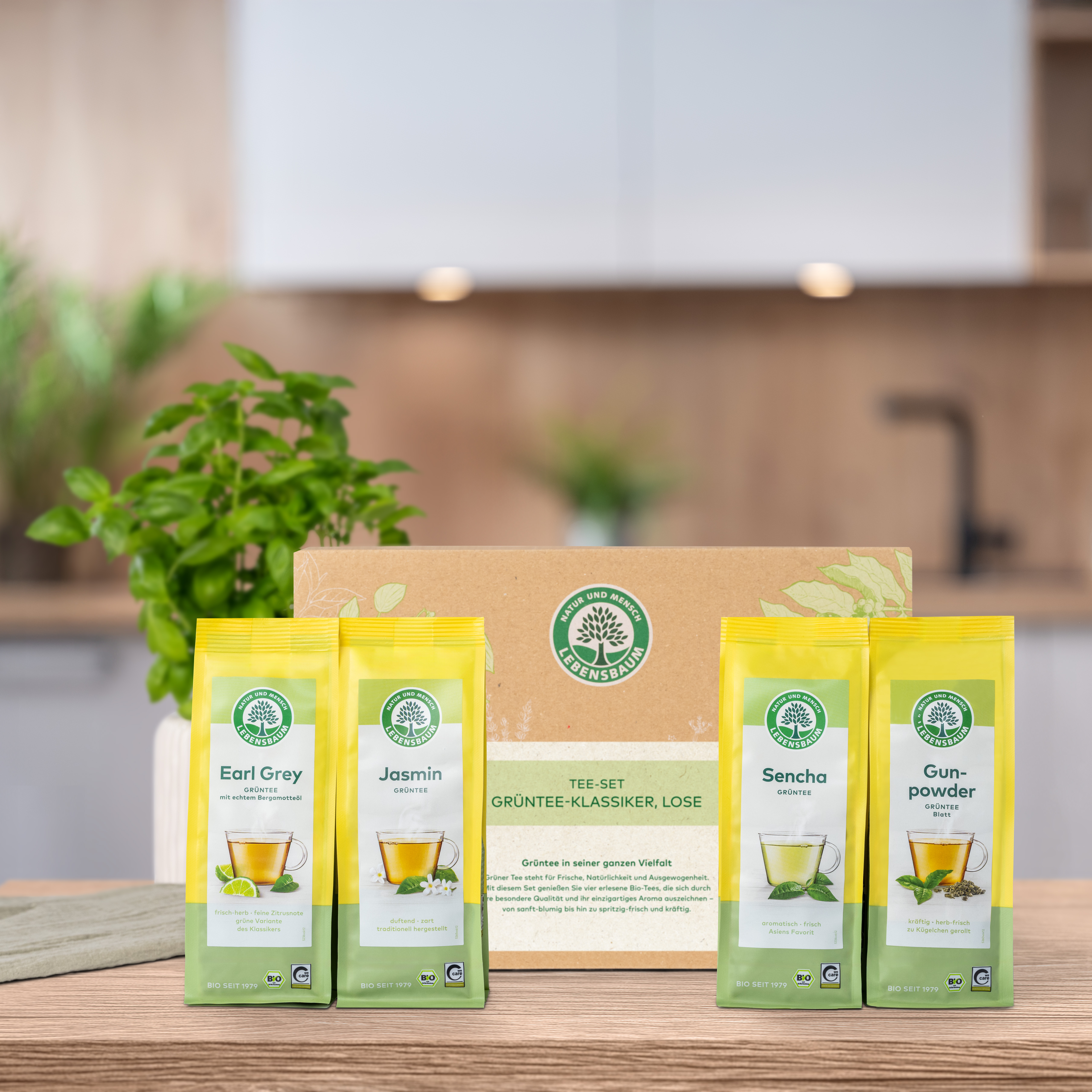 Verschlossenes Geschenk-Set steht auf einem Holztisch in der Küche. Vor der Geschenk-Set Verpackung  stehen die darin enthaltenen Produkte