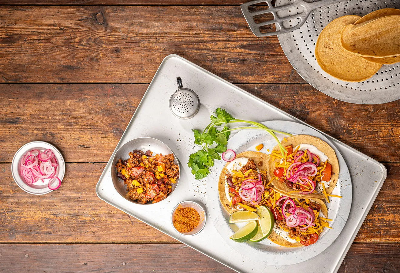 Tacos auf einem weißen Teller mit Limettenspalten