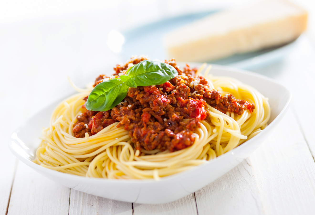 Spaghetti Bolognese in einer weißen Schüssel mit Basilikum garniert