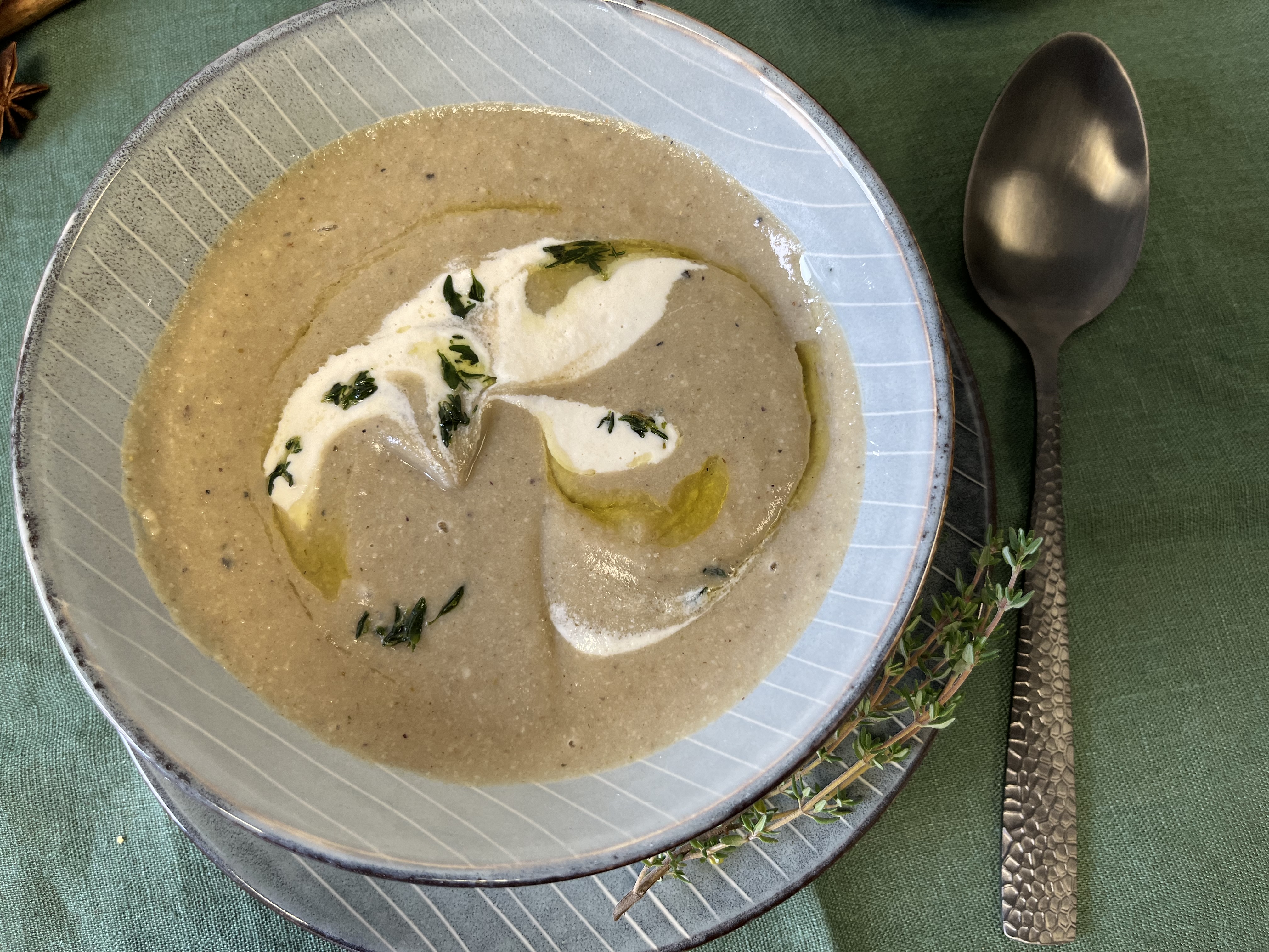 Maronencremesuppe in einer blauen Schale, mit Sahne garniert auf einer grünen Tischdecke