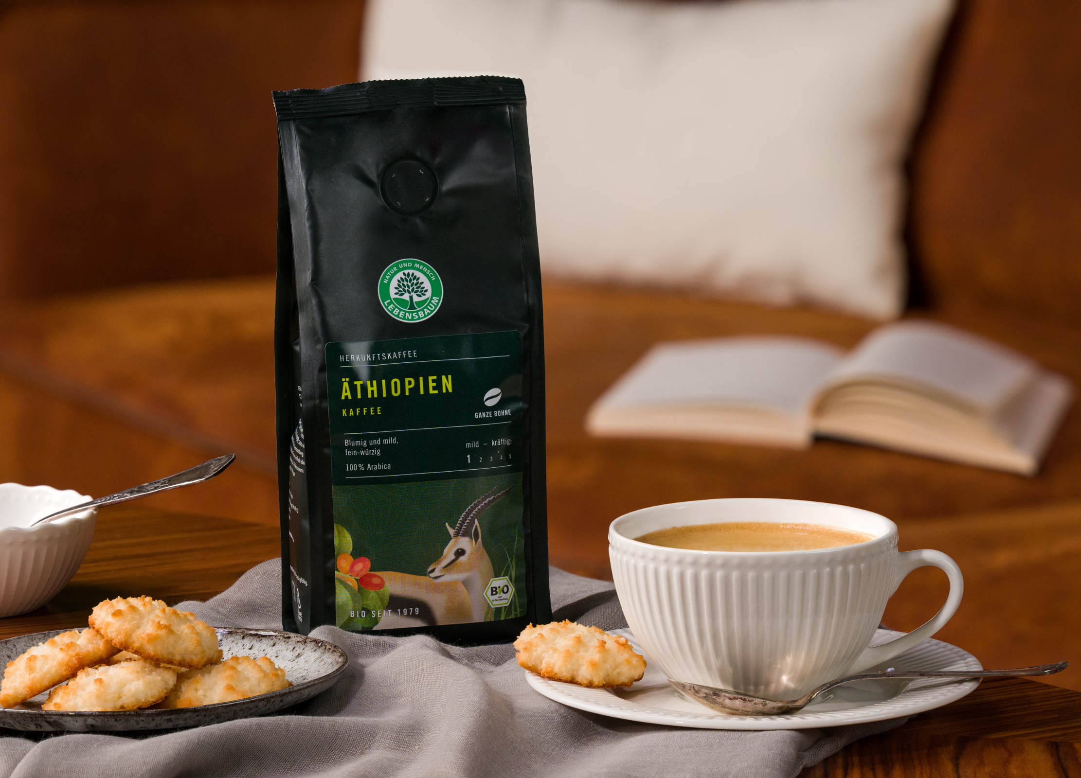 Kaffee Äthiopien von Lebensbaum mit Tasse Kaffee, Gebäck und einem offenen Buch im Hintergrund