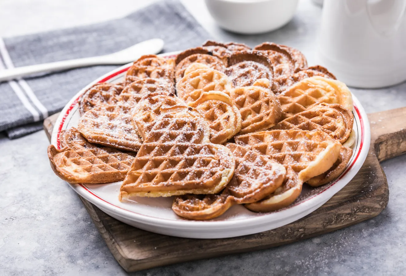  Wintergewürz-Waffeln auf einem weißen Teller auf einem Holzbrett mit Puderzucker garniert