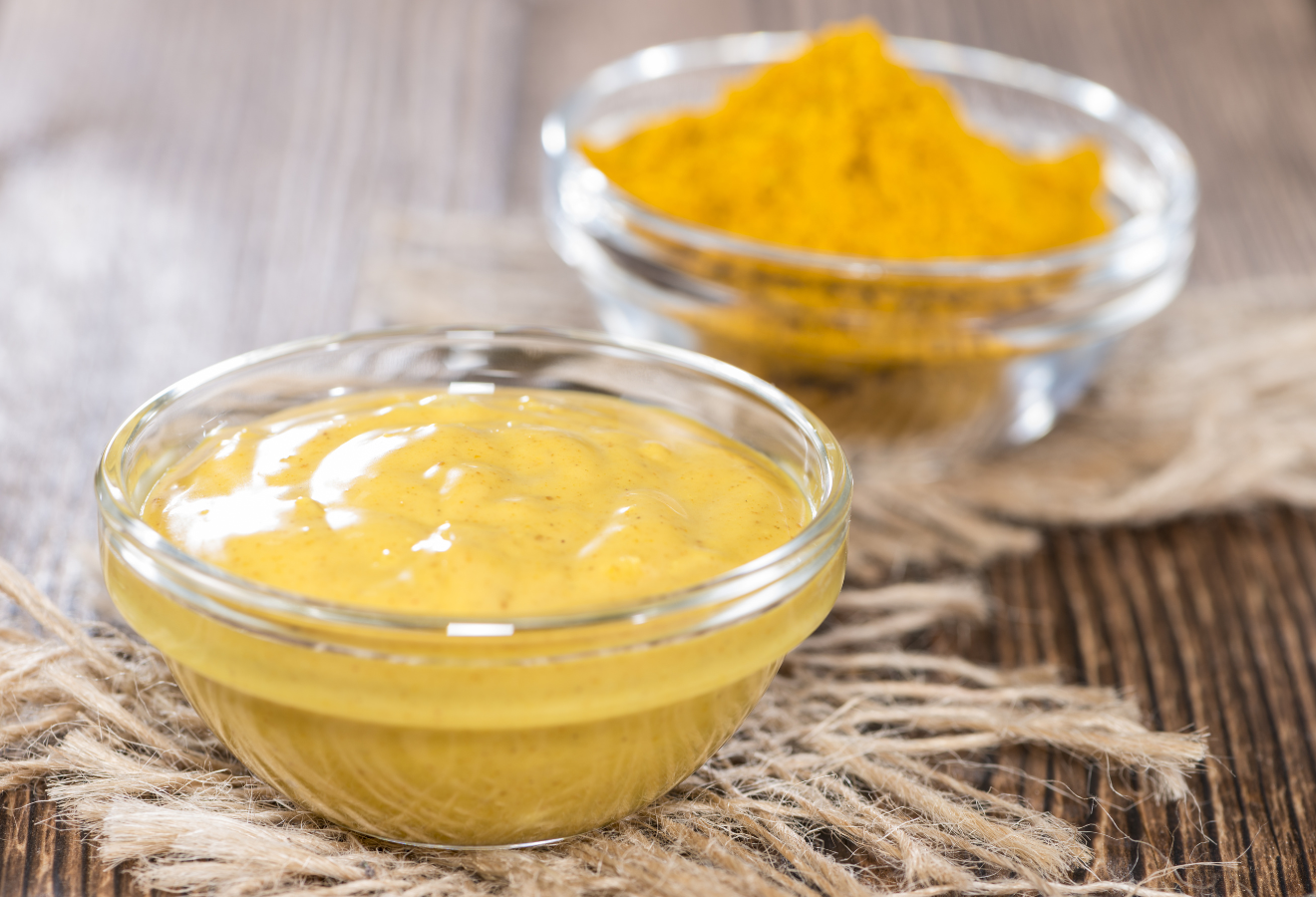 Curry-Marinade in einem Schälchen mit Curry im Hintergrund