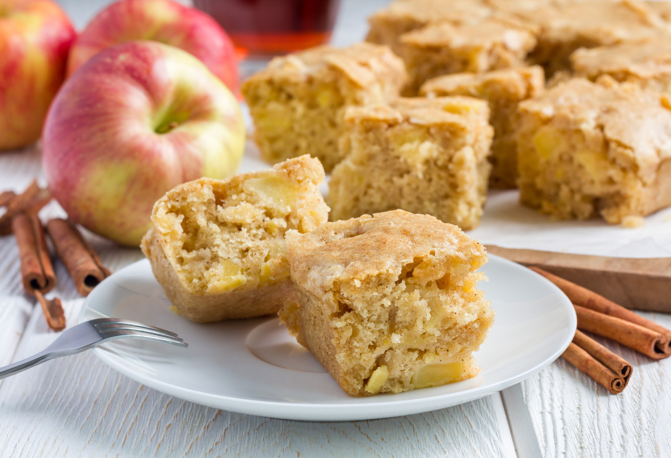 Bratapfel-Blondies mit Zimtstangen und Äpfeln im Hintergrund