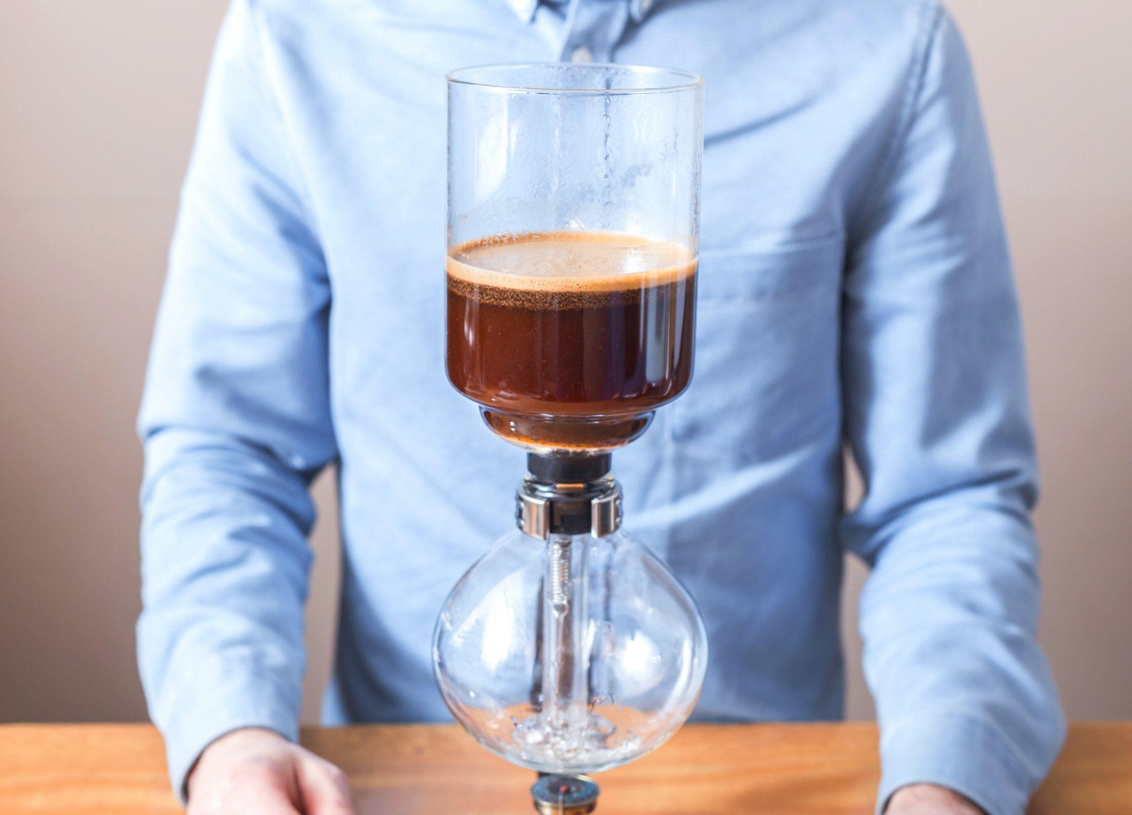Kaffee zieht im oberen Glasbehälter eines Syphon-Kaffeebereiters, bevor er durch Unterdruck in die untere Glaskammer gesogen wird