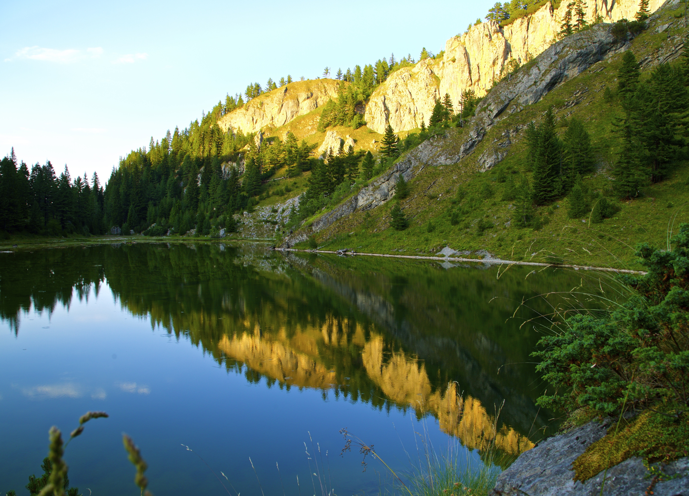 Bergsee mit Spiegelung von Felsen und Nadelbäumen in ruhiger Naturkulisse in Kosovo