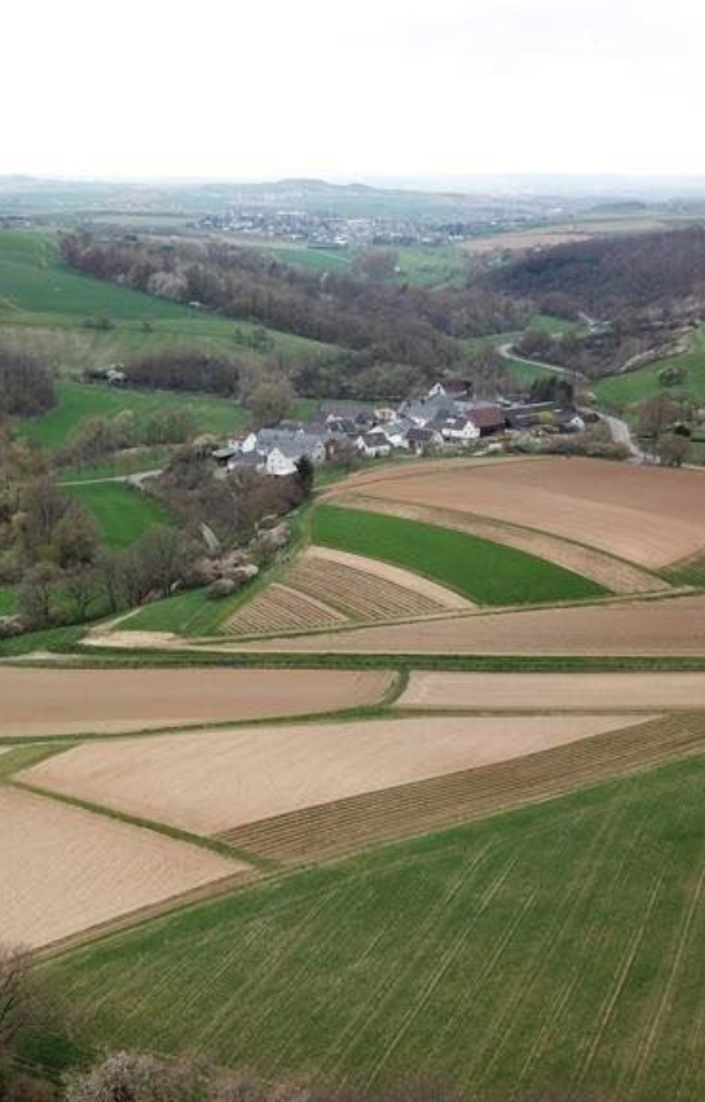 Blick auf Hünfelden mit umliegenden Feldern und sanften Hügeln
