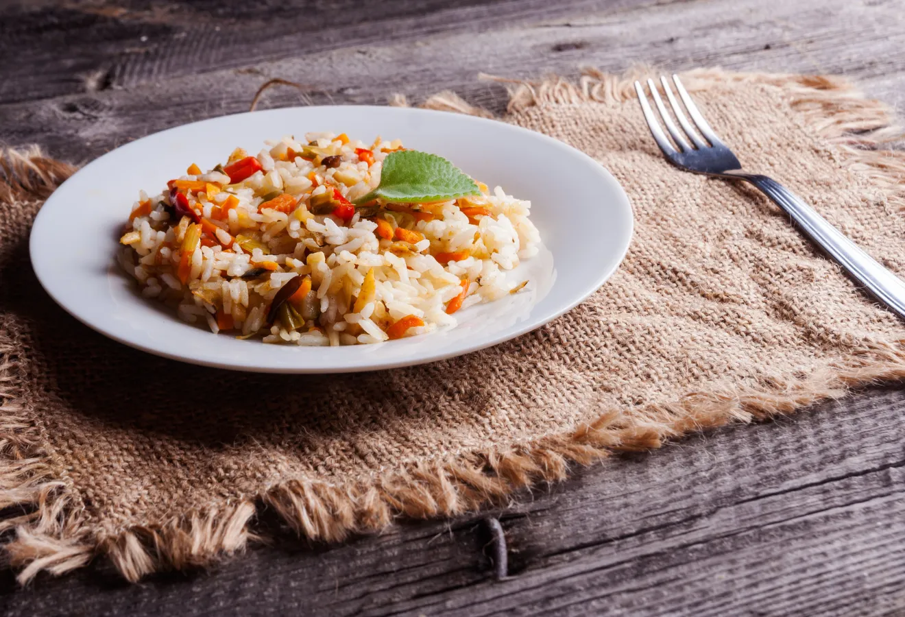 Thai-Risotto auf einem weißen Teller, daneben eine Gabel
