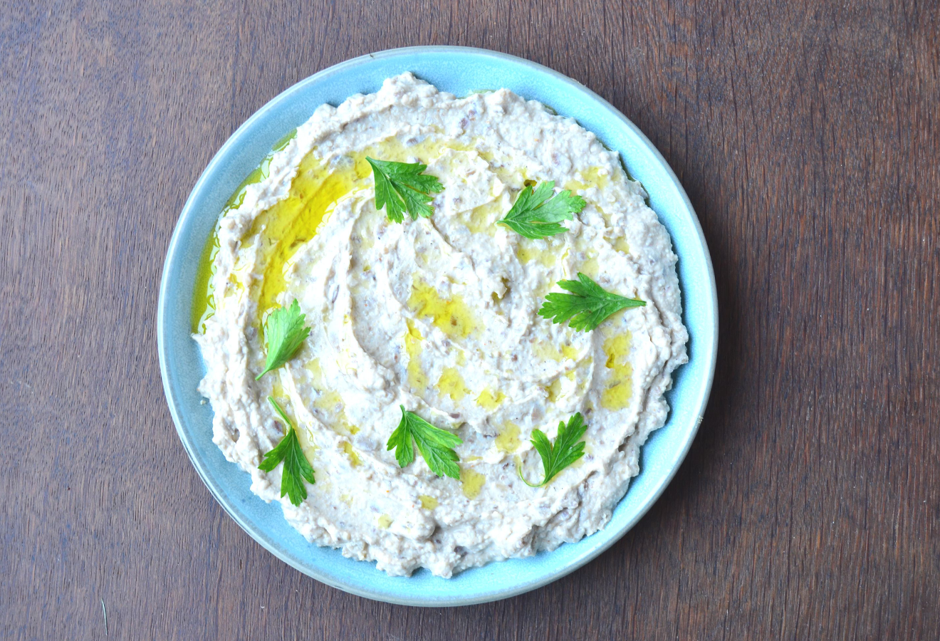 Maronen-Hummus in einer Schüssel mit Öl und Kräutern garniert