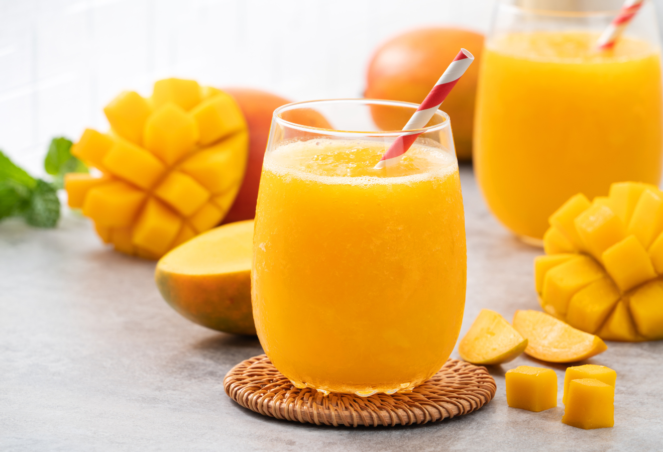 Mango-Cocktail in einem Glas, im Hintergrund Mangos