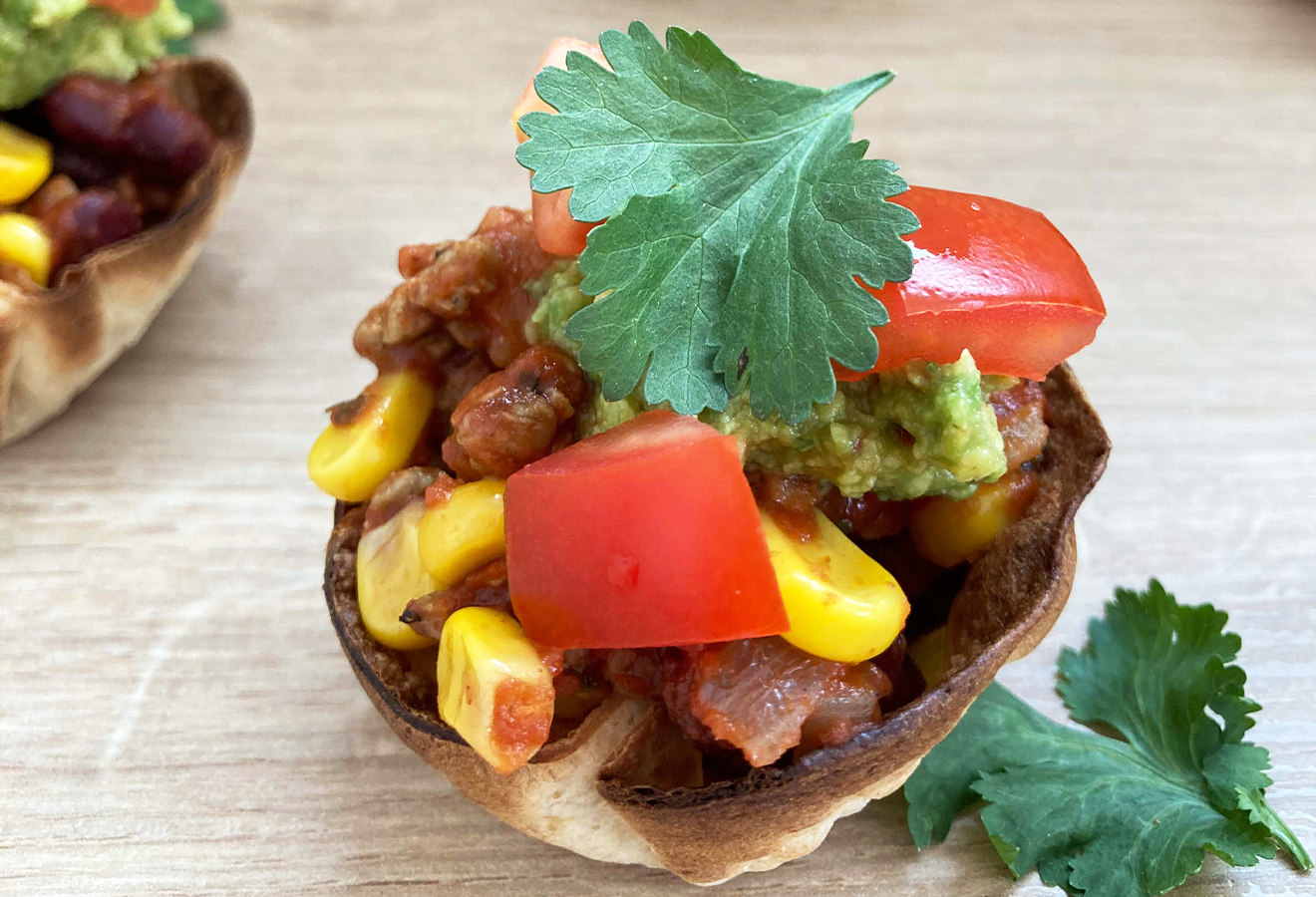 Taco-Cups auf einem Holzbrett mit Koriander garniert