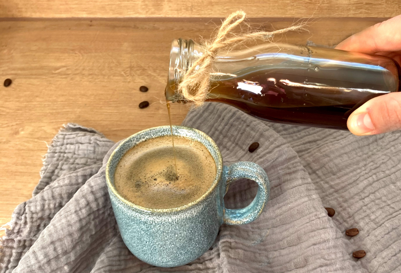 Chai-Sirup, vegan in einer Flasche, wird in eine Tasse Kaffee gegossen