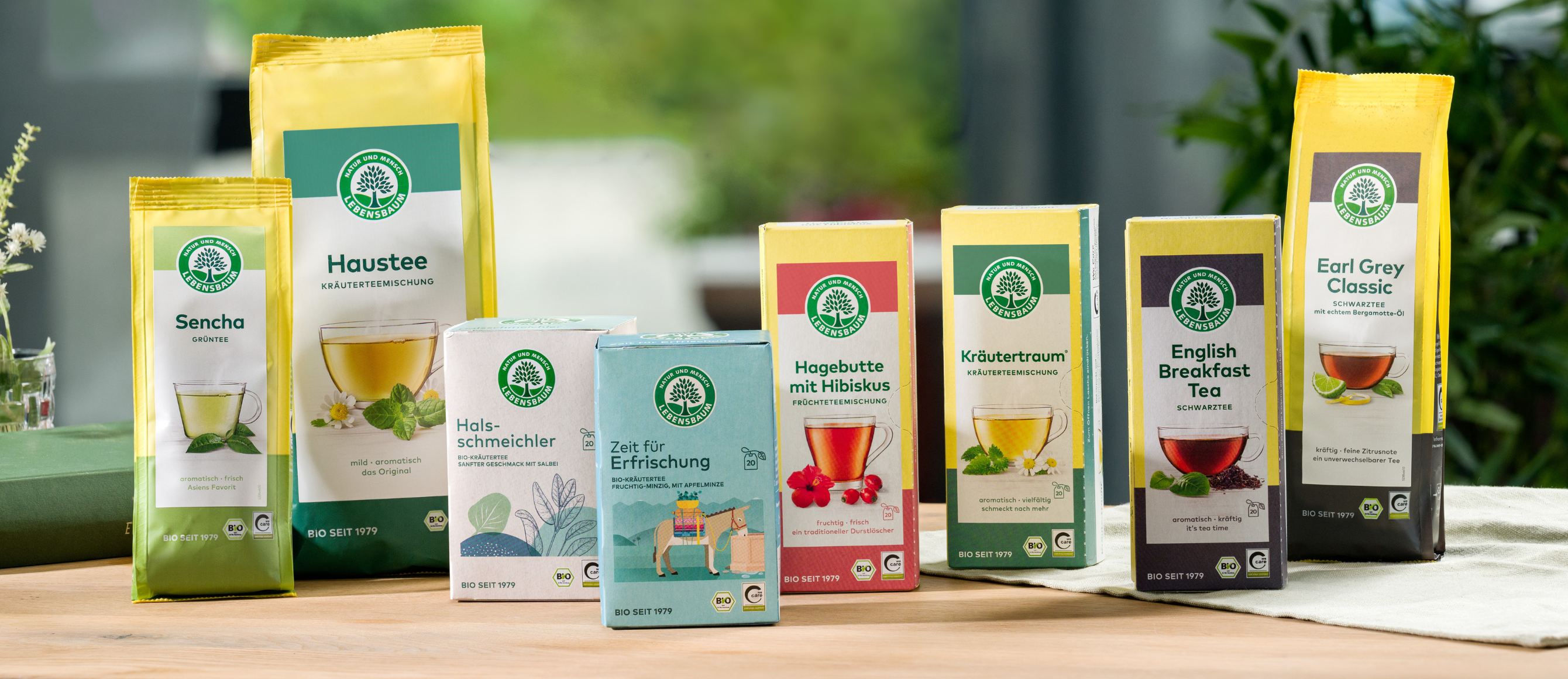 Verschiedene Sorten Bio-Lebensbaum Tee in bunten Verpackungen auf einem Holztisch