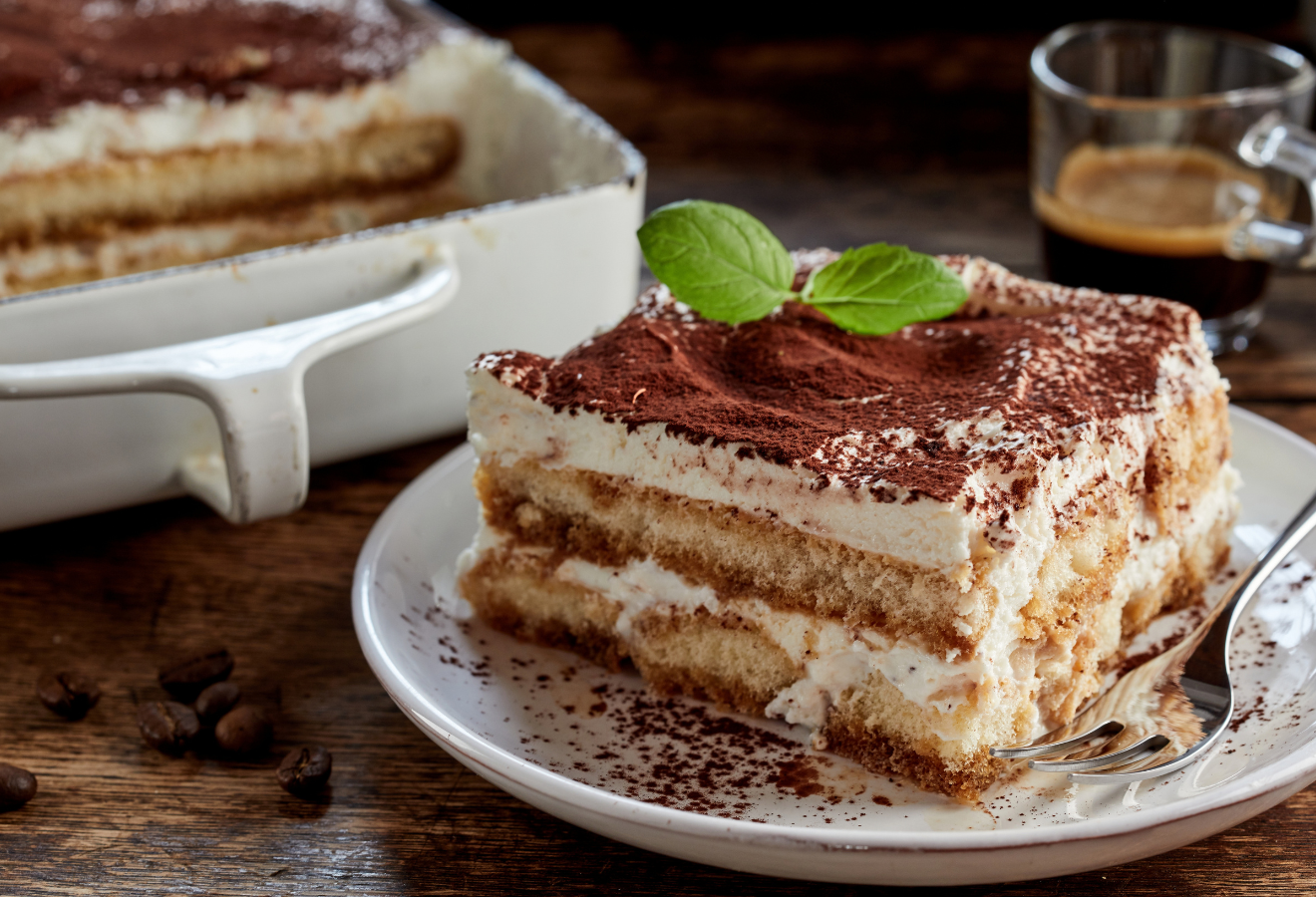Tiramisu auf einem weißen Teller mit Minzblättern garniert