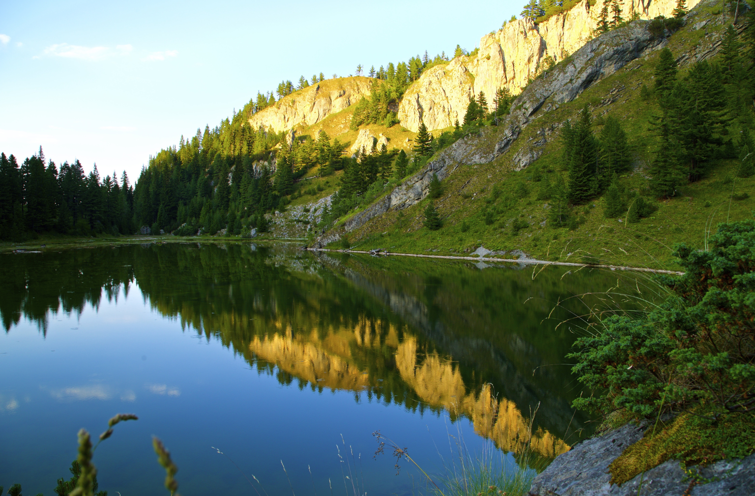 Bergsee mit Spiegelung von Felsen und Nadelbäumen in ruhiger Naturkulisse aus Kosovo