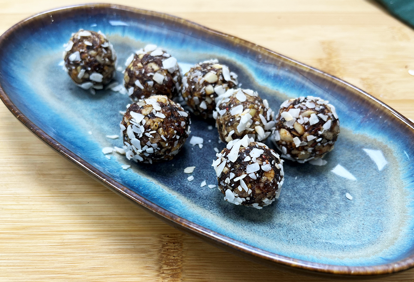 Energy Balls auf einem Teller mit Kokosraspeln bestreut