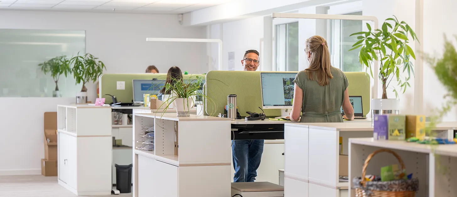 Menschen arbeiten an höhenverstellbaren Schreibtischen in unserem modernen Großraumbüro in Diepholz
