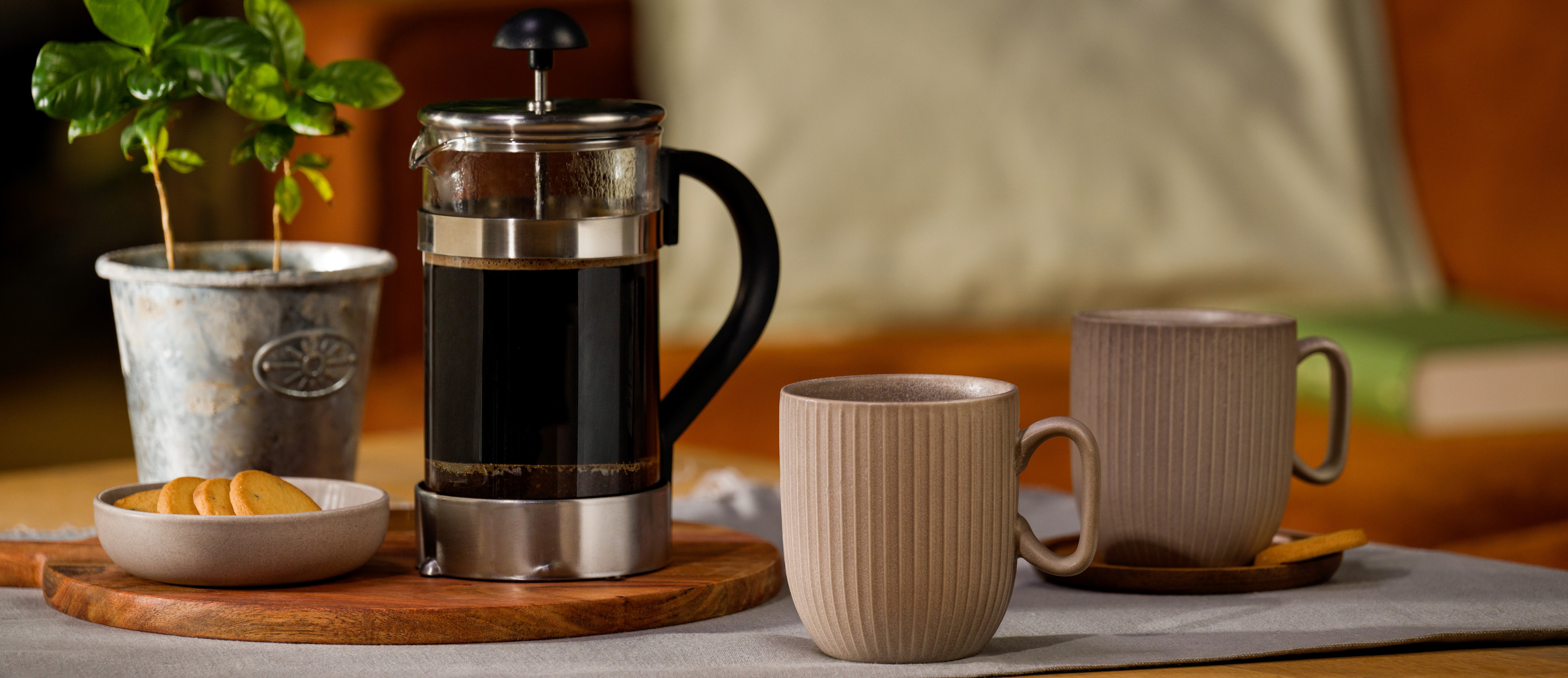 Frenchpress-Kanne mit Kaffee darin, zwei Tassen daneben