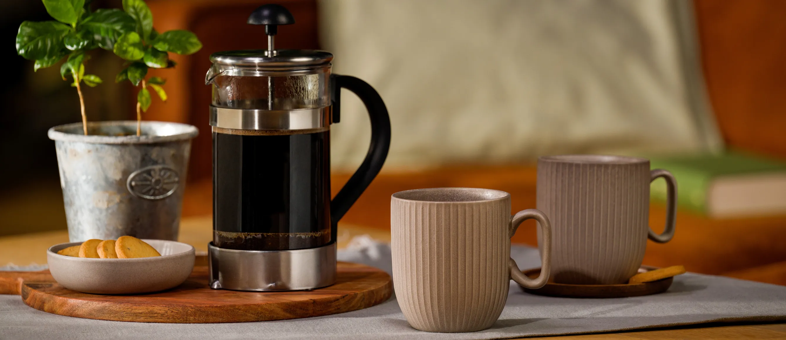 Frenchpress-Kanne mit Kaffee darin, zwei Tassen daneben