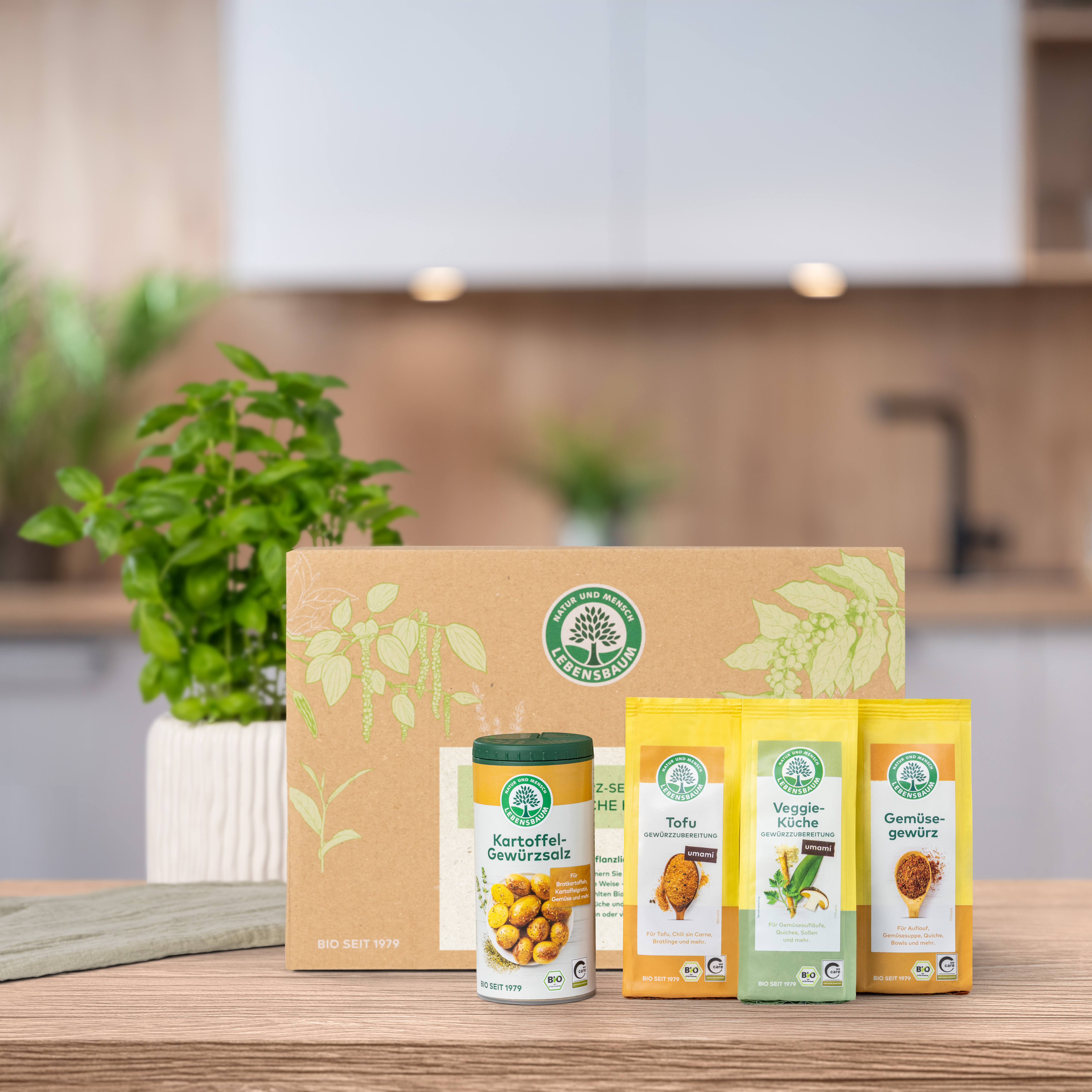 Verschlossenes Geschenk-Set steht auf einem Holztisch in der Küche. Vor der Geschenk-Set Verpackung  stehen die darin enthaltenen Produkte