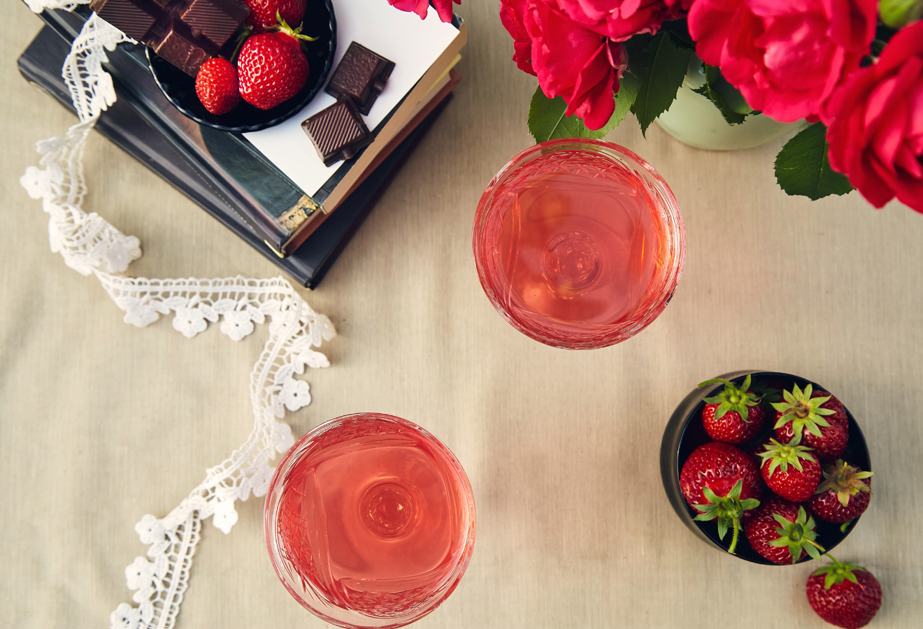 La vie en rose in 2 Gläsern, daneben eine Schale Erdbeeren
