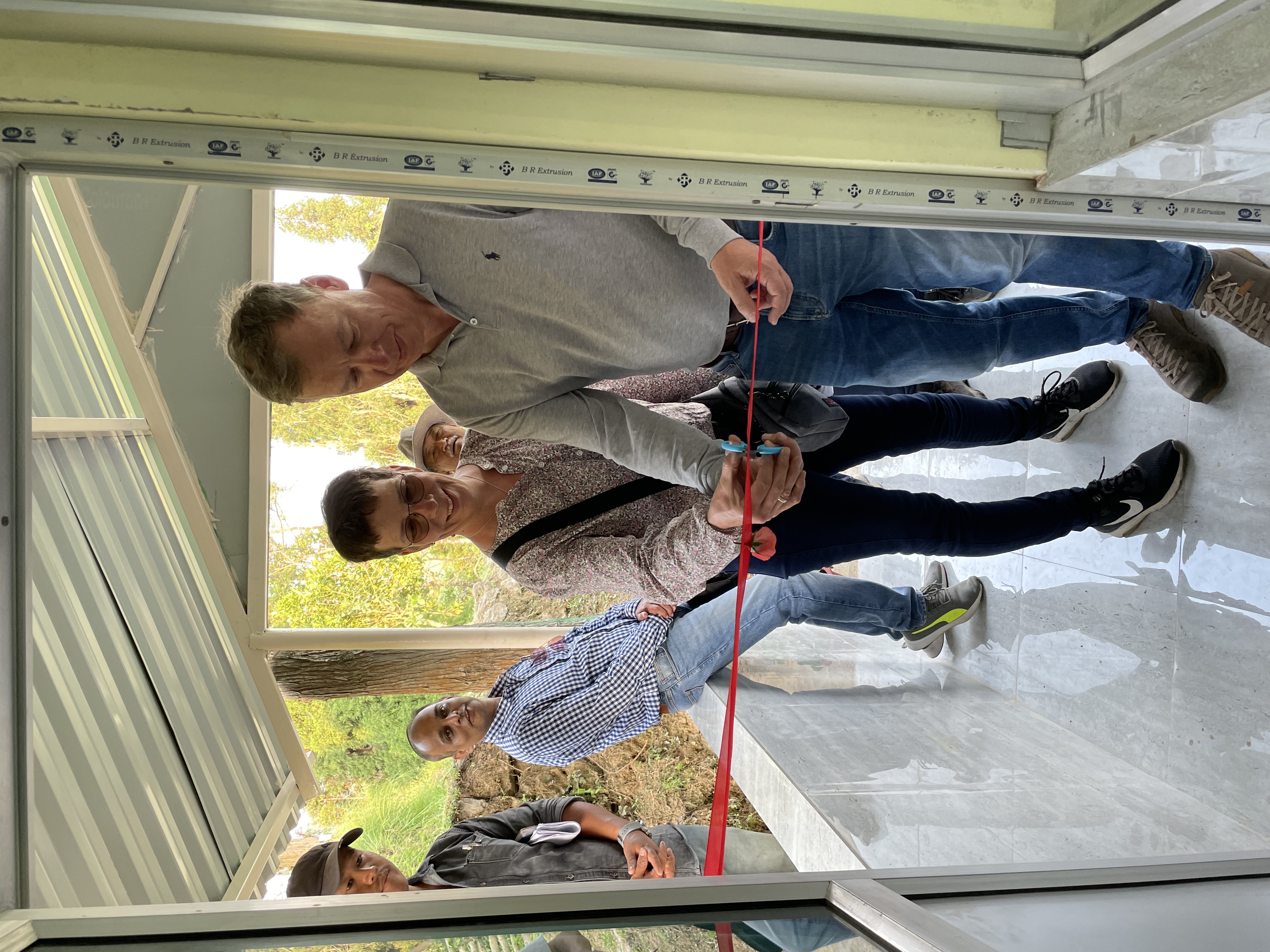 Mann und Frau schneiden feierlich ein rotes Band bei einer Eröffnung durch