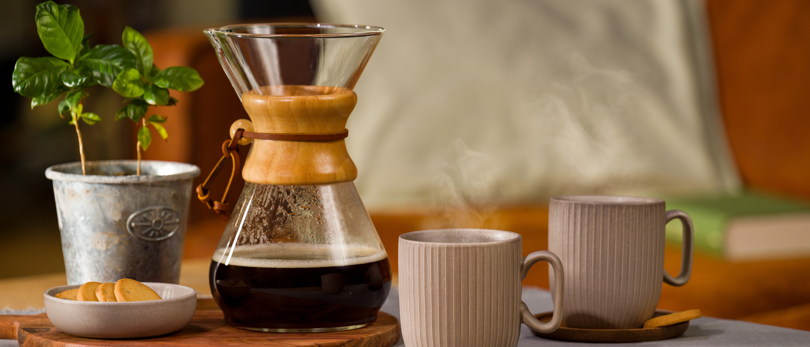Chemex mit Kaffee darin, davor zwei Tassen