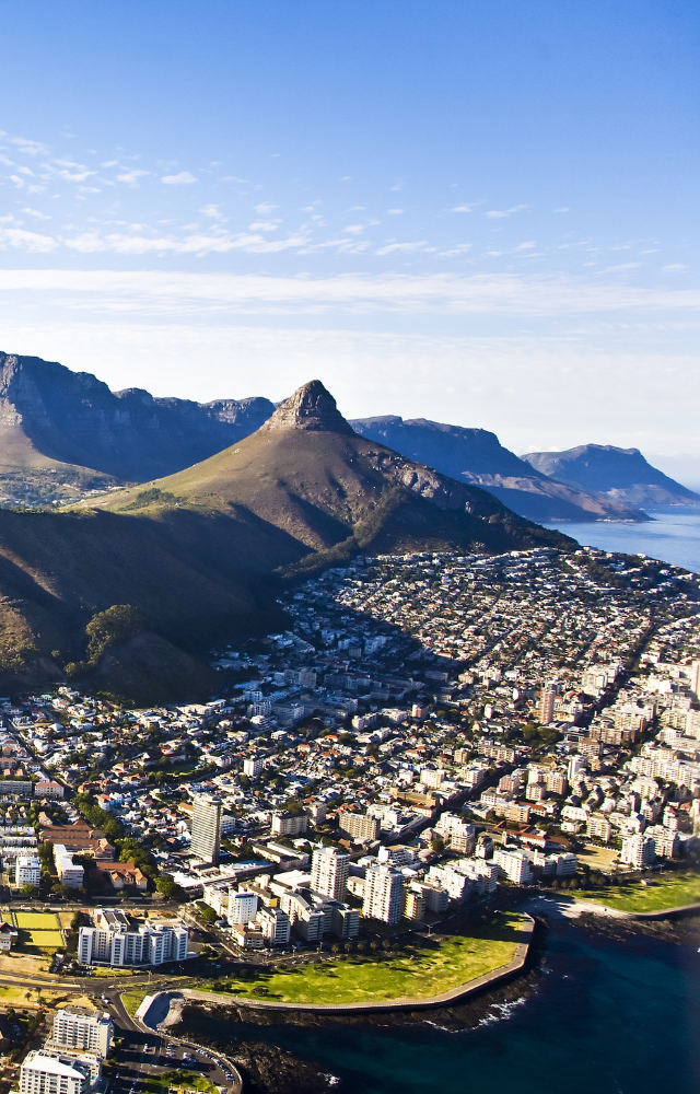Stadt an der Küste mit Bergen im Hintergrund, darunter ein markanter spitzer Gipfel in Südafrika